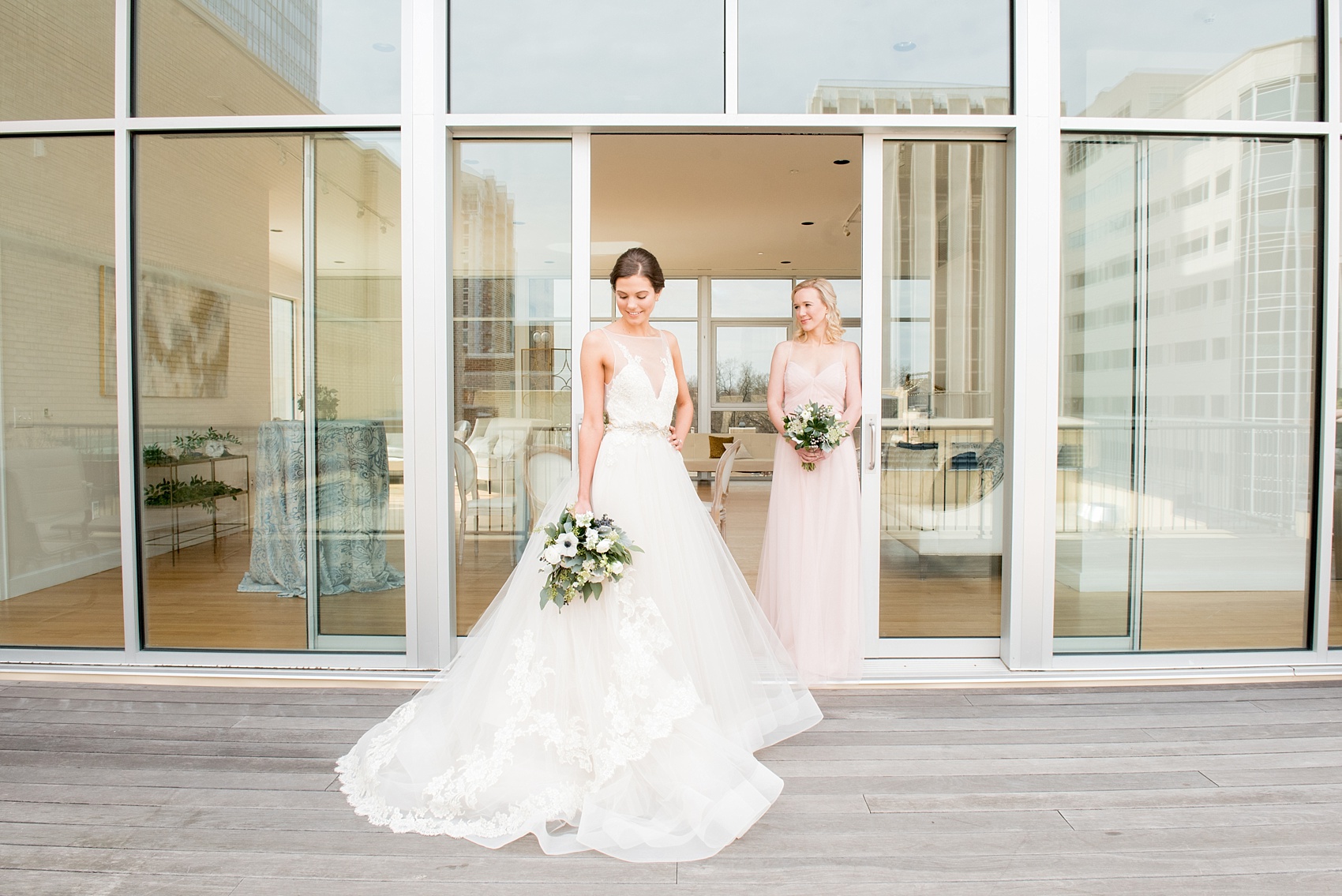 The Glass Box Raleigh wedding photos by Mikkel Paige Photography. Picture of the bride in a Lazaro gown in this modern downtown venue. The bridesmaid wore a pink Hayley Paige occasion gown.