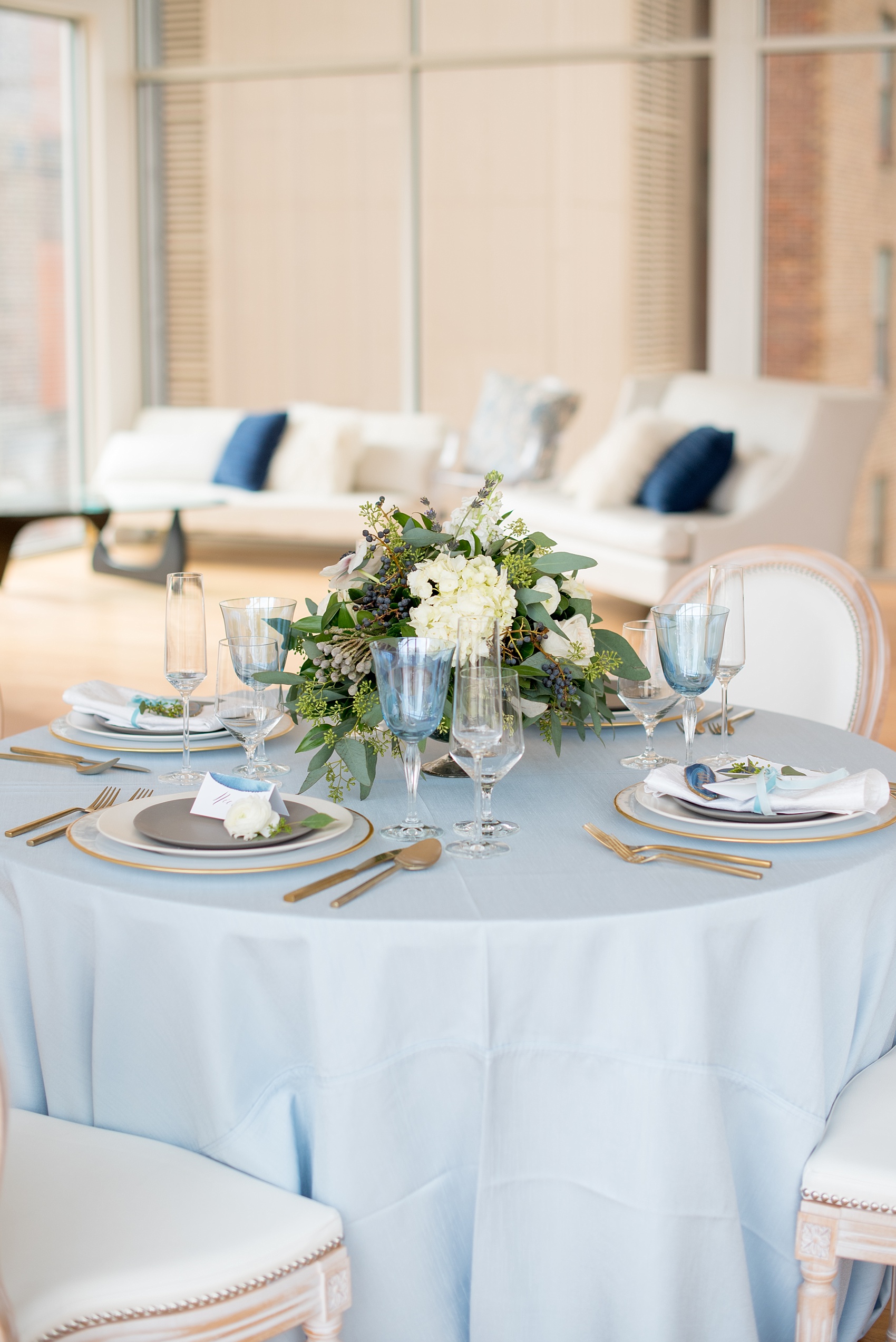 The Glass Box Raleigh wedding photos by Mikkel Paige Photography. Picture of a blue and white table with grey and gold place settings in this modern downtown venue.