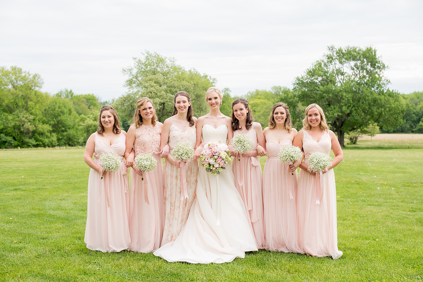 Waveny House wedding photos in Connecticut by Mikkel Paige Photography. Picture of the bride in a strapless gown with her bridesmaids in pink dresses, and maid of honor in a pink floral pattern gown. Bridesmaids held Baby's Breath bouquets.