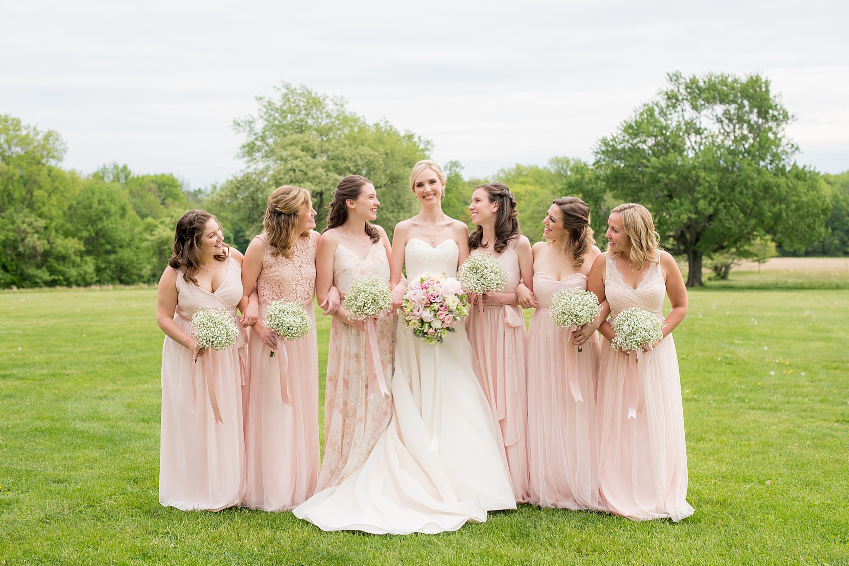 Waveny House wedding photos in Connecticut by Mikkel Paige Photography. Picture of the bride in a strapless gown with her bridesmaids in pink dresses, and maid of honor in a pink floral pattern gown. Bridesmaids held Baby's Breath bouquets.