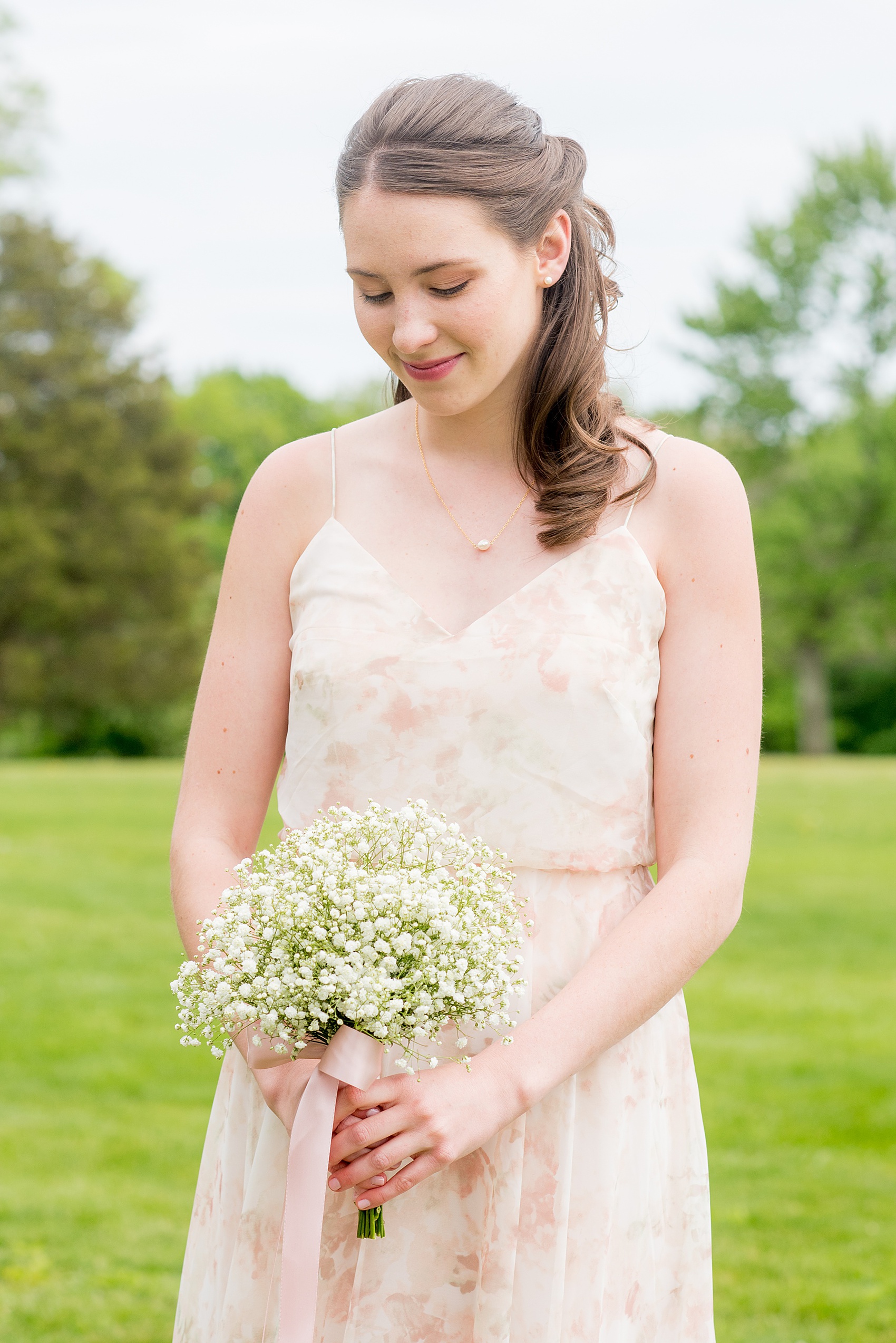Waveny House wedding photos in Connecticut by Mikkel Paige Photography. Picture of the maid of honor in a pink floral pattern gown holding a Baby's Breath bouquet.