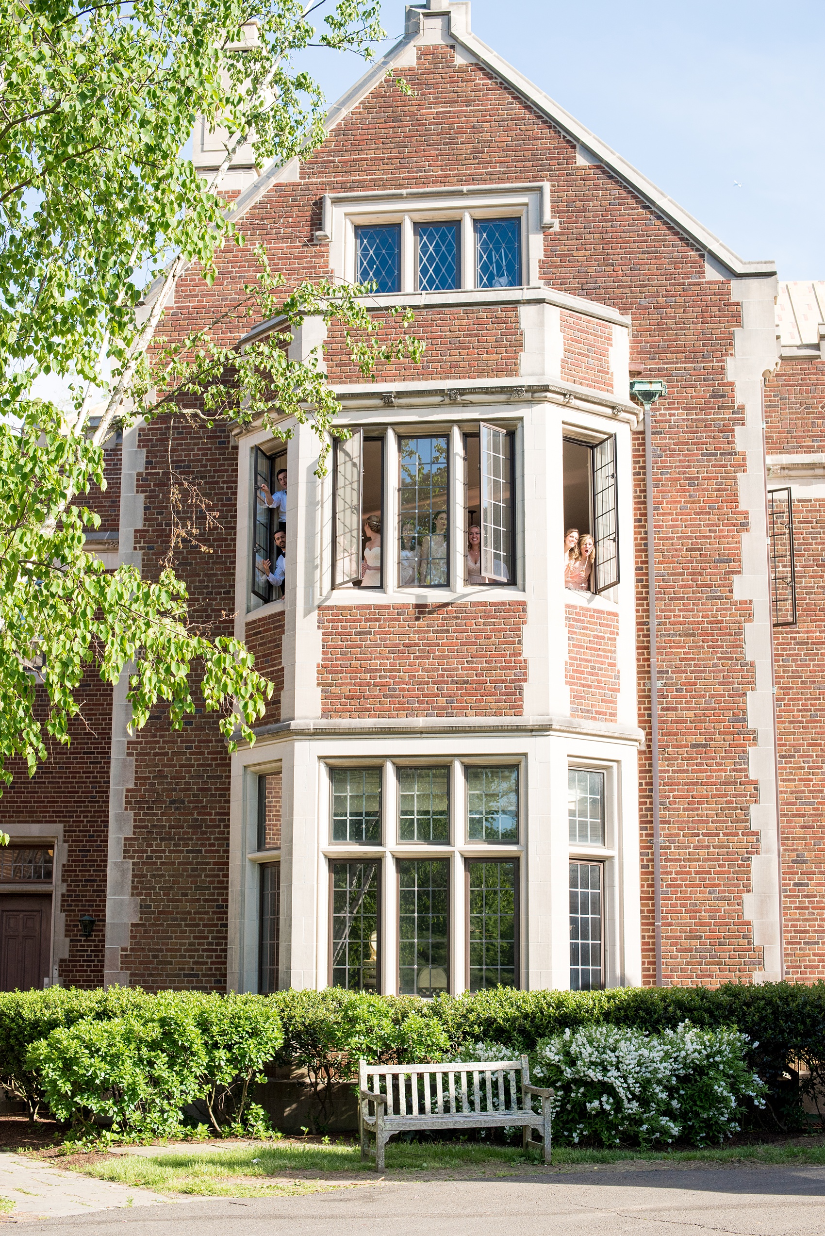 Waveny House wedding photos in Connecticut by Mikkel Paige Photography. Picture of the brick house with the bridal party looking through the windows.