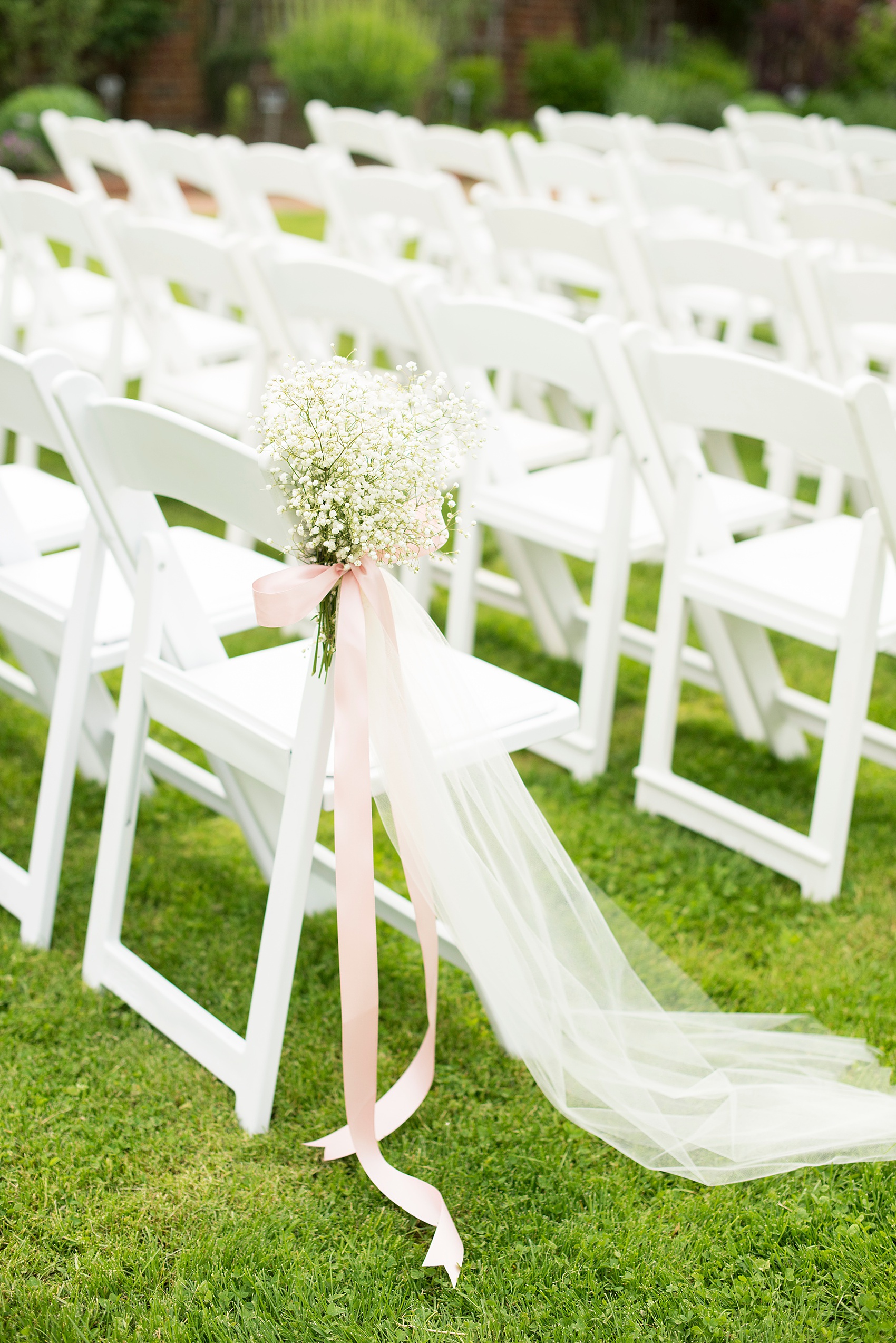 Waveny House wedding photos in Connecticut by Mikkel Paige Photography. Detail picture of the white ceremony chairs and baby's breath bouquets tied with tulle and pink ribbon.