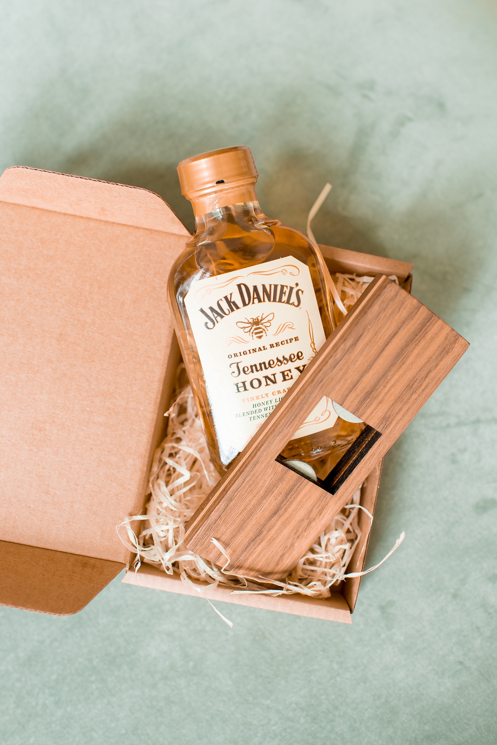 Mikkel Paige Photography photos from a wedding in Durham, North Carolina at The Rickhouse. Detail image of the groomsmen gifts. Bottle of whiskey with a Danish wood bottle opener.
