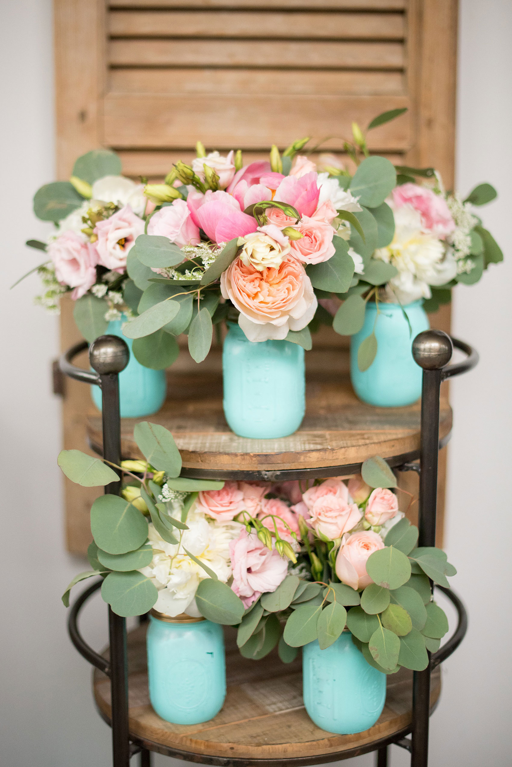 Mikkel Paige Photography photos from a wedding in Durham, North Carolina. Picture of the bridesmaids bouquets of peonies, eucalyptus and ranunculus in blue mason jars at The Rickhouse.