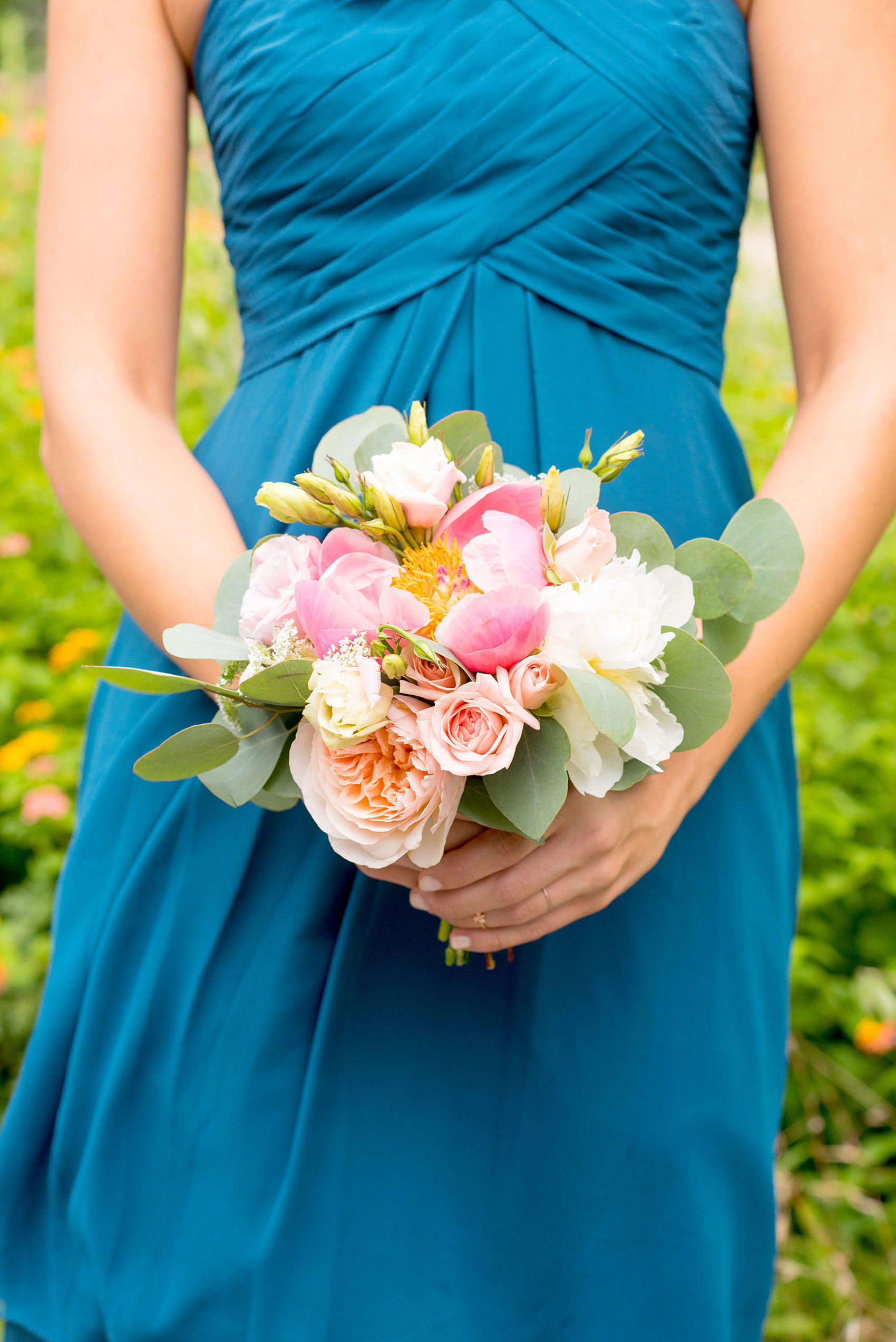 Mikkel Paige Photography photos from a wedding in Durham, North Carolina. Picture of the maid of honor with yellow flowers behind her, in a teal dress, holding a bouquet of peonies and eucalyptus.