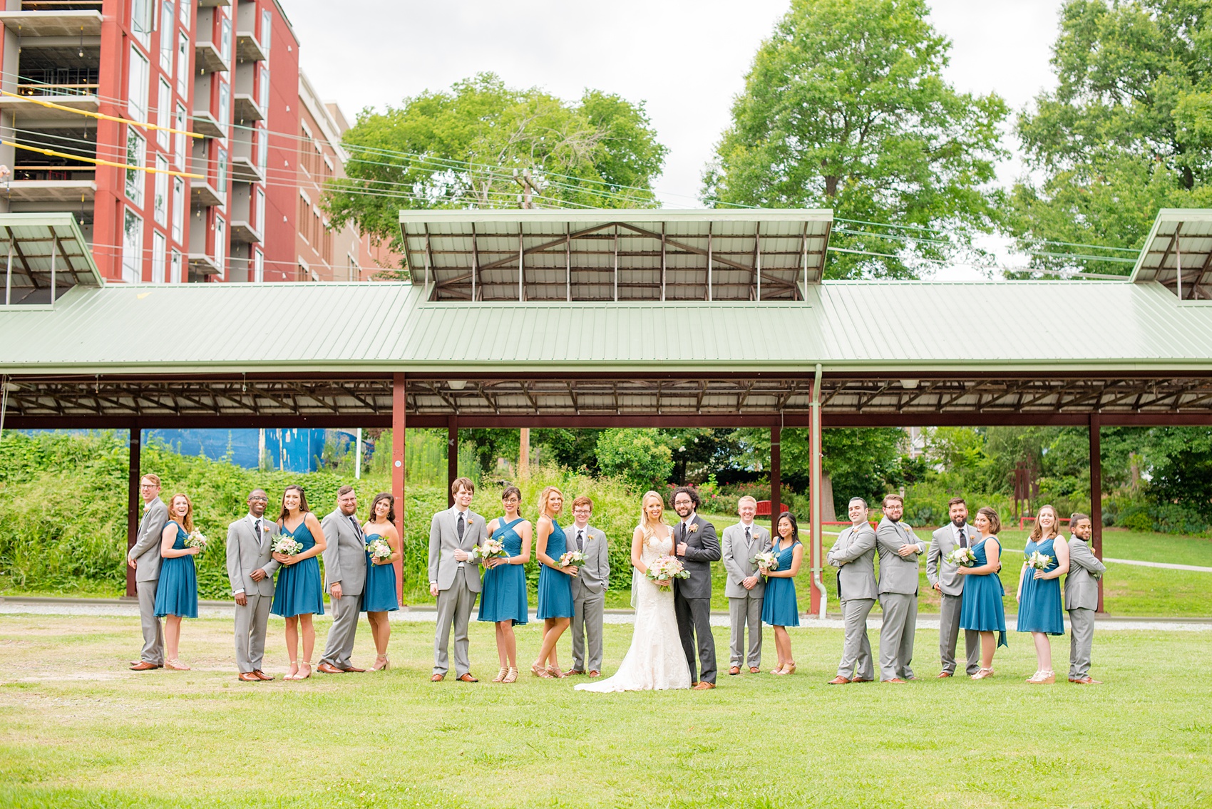 Mikkel Paige Photography photos from a wedding in Durham, North Carolina. Picture of the large wedding party - with the bridesmaids in teal and groomsmen in grey - in a Vogue-like photo in the park.