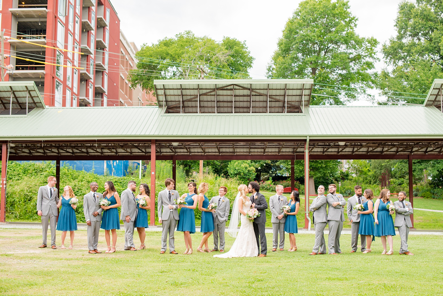 Mikkel Paige Photography photos from a wedding in Durham, North Carolina. Picture of the large wedding party - with the bridesmaids in teal and groomsmen in grey - in a Vogue-like photo in the park.