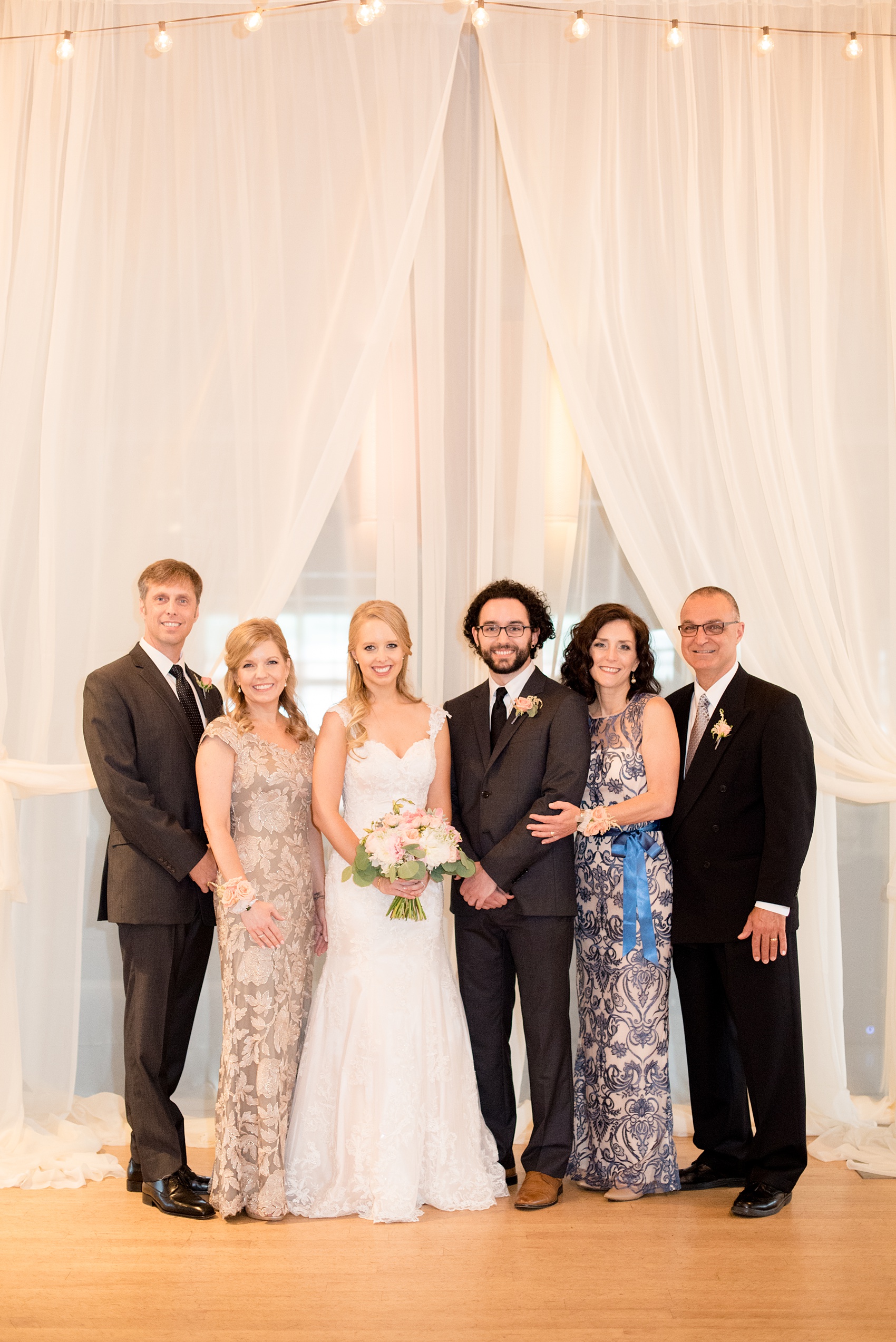 Mikkel Paige Photography photos from a wedding in Durham, North Carolina. Picture of the bride, groom and their parents in front of draping at The Rickhouse.