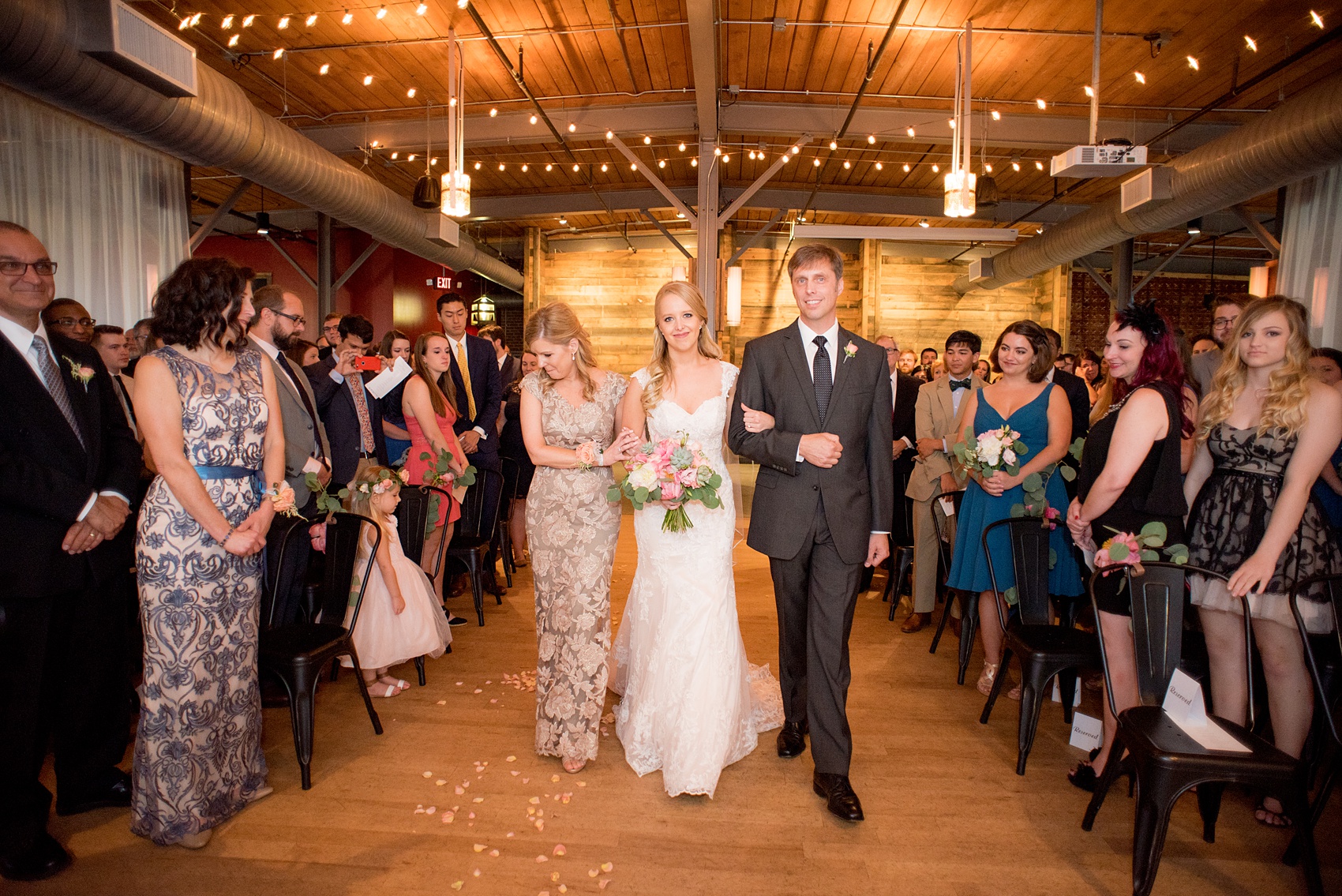 Mikkel Paige Photography photos from a wedding at The Rickhouse in Durham, North Carolina. Picture of the bride and her parents walking down the aisle.