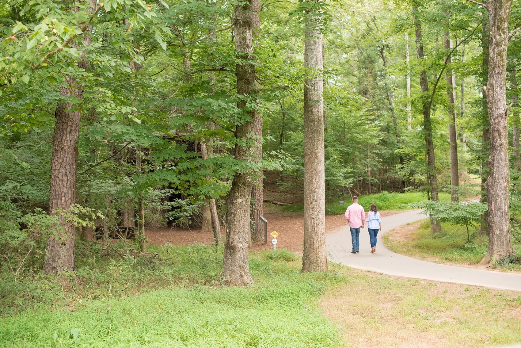 Mikkel Paige Photography photos of an engagement session at Eno Riverwalk in Hillsborough, North Carolina. Picture of bride and groom walking on a path in the forest.