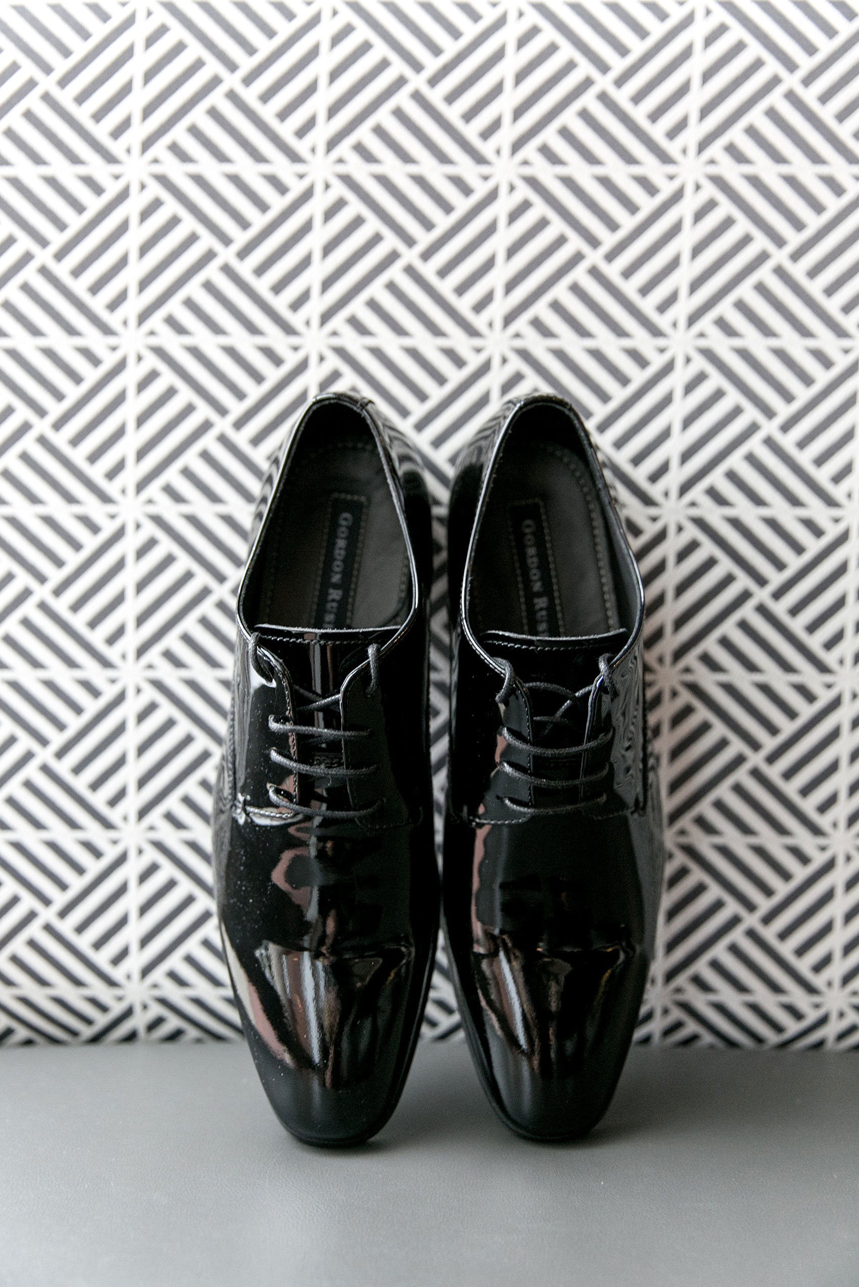 Mikkel Paige Photography pictures of a Westbury Manor wedding on Long Island. Detail photo the groom's shoes with a black and white geometric background.