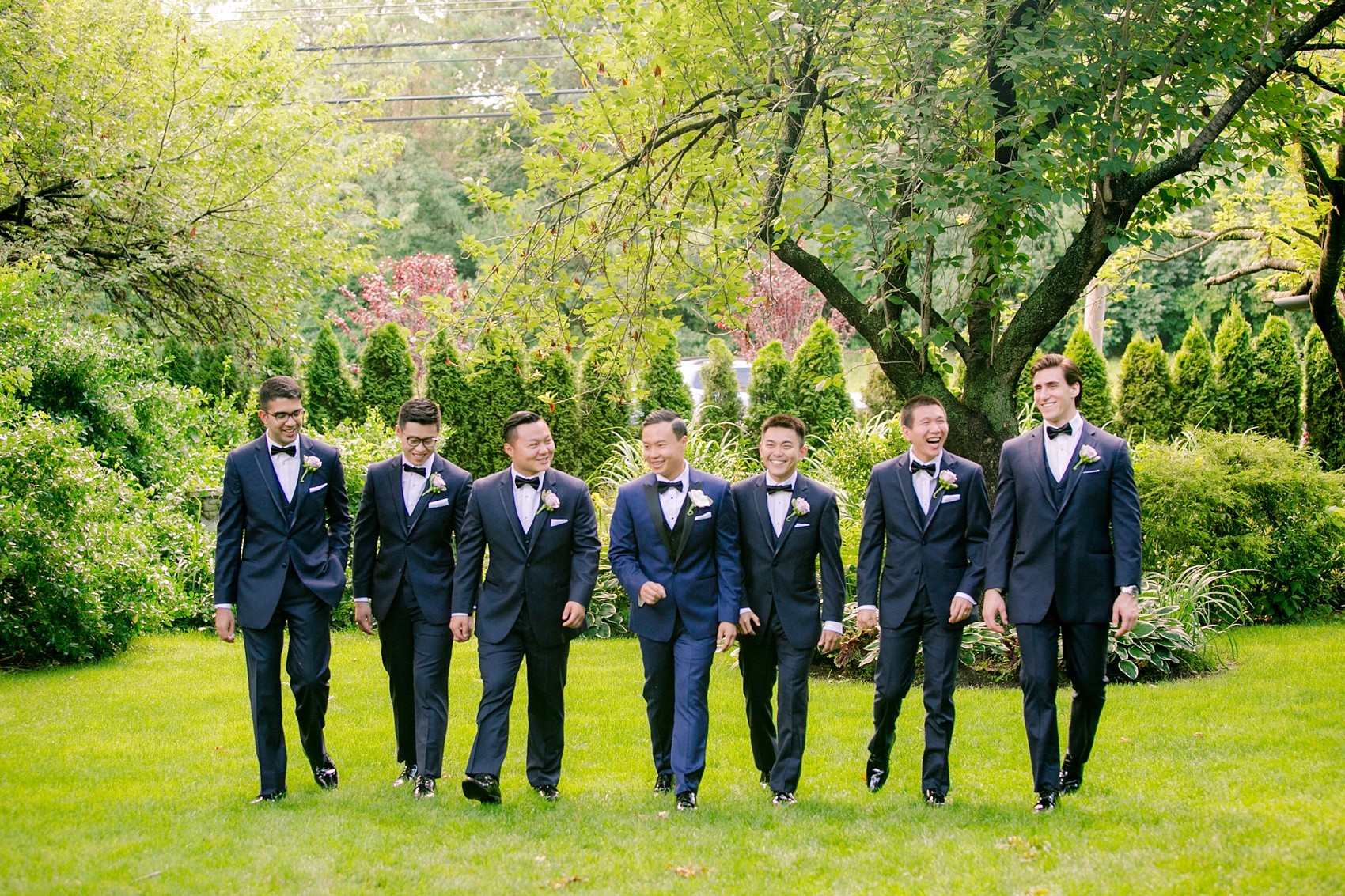 Mikkel Paige Photography pictures of a Westbury Manor wedding on Long Island. Candid photo of the groomsmen in navy suits and bow ties.