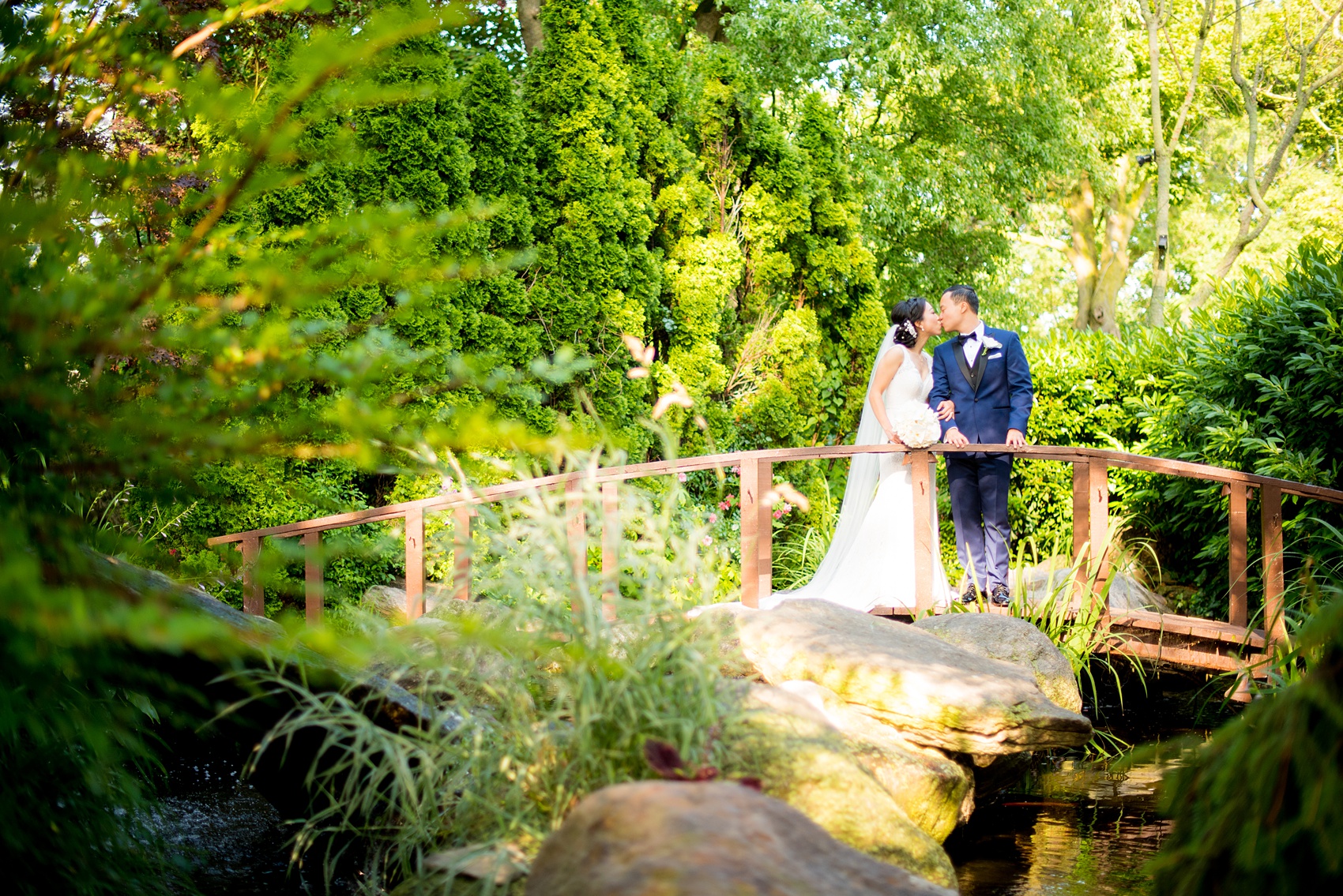 Mikkel Paige Photography pictures of a Westbury Manor wedding on Long Island. Photo of the bride and groom on a bridge in the garden.