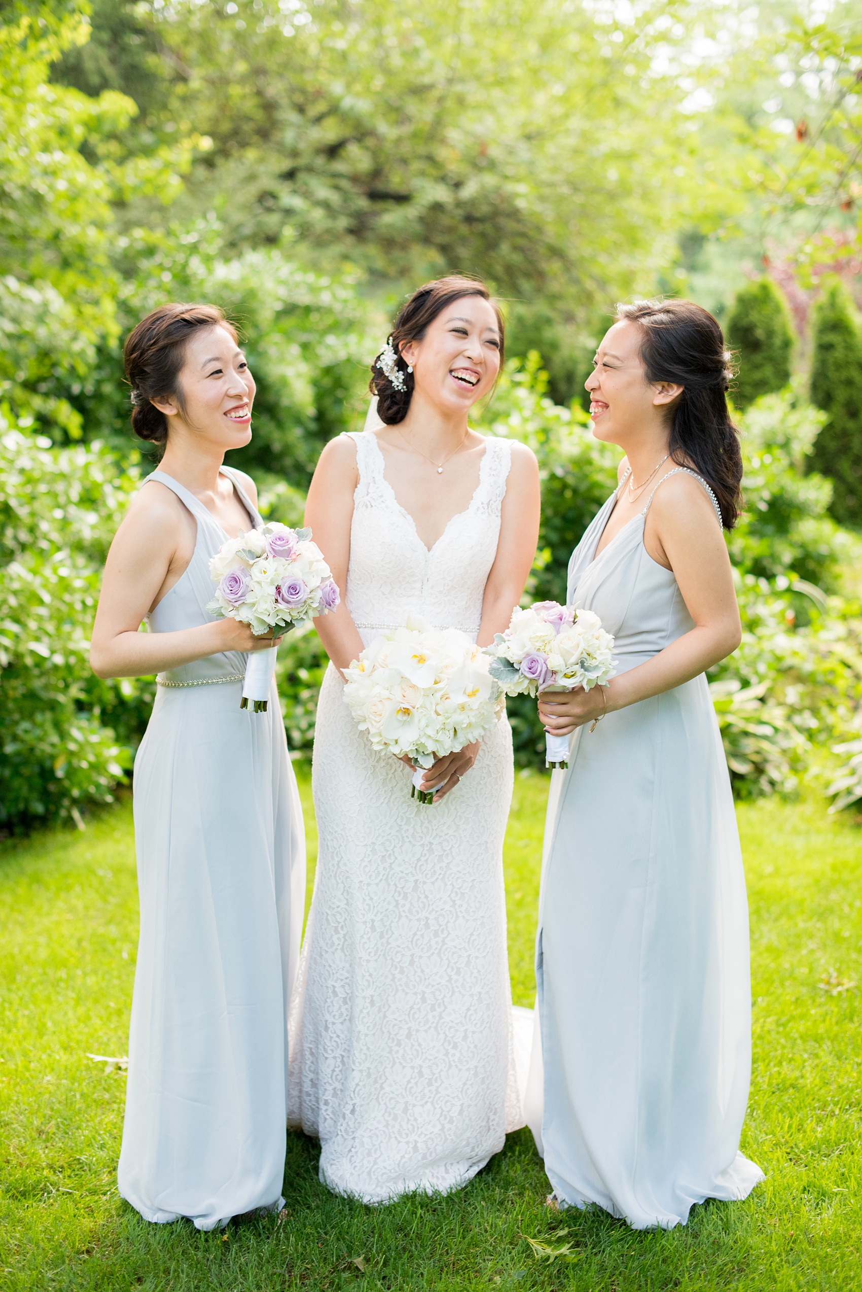 Mikkel Paige Photography pictures of a Westbury Manor wedding on Long Island. Photo of the bride and her bridesmaid sisters in grey gowns with bouquets.