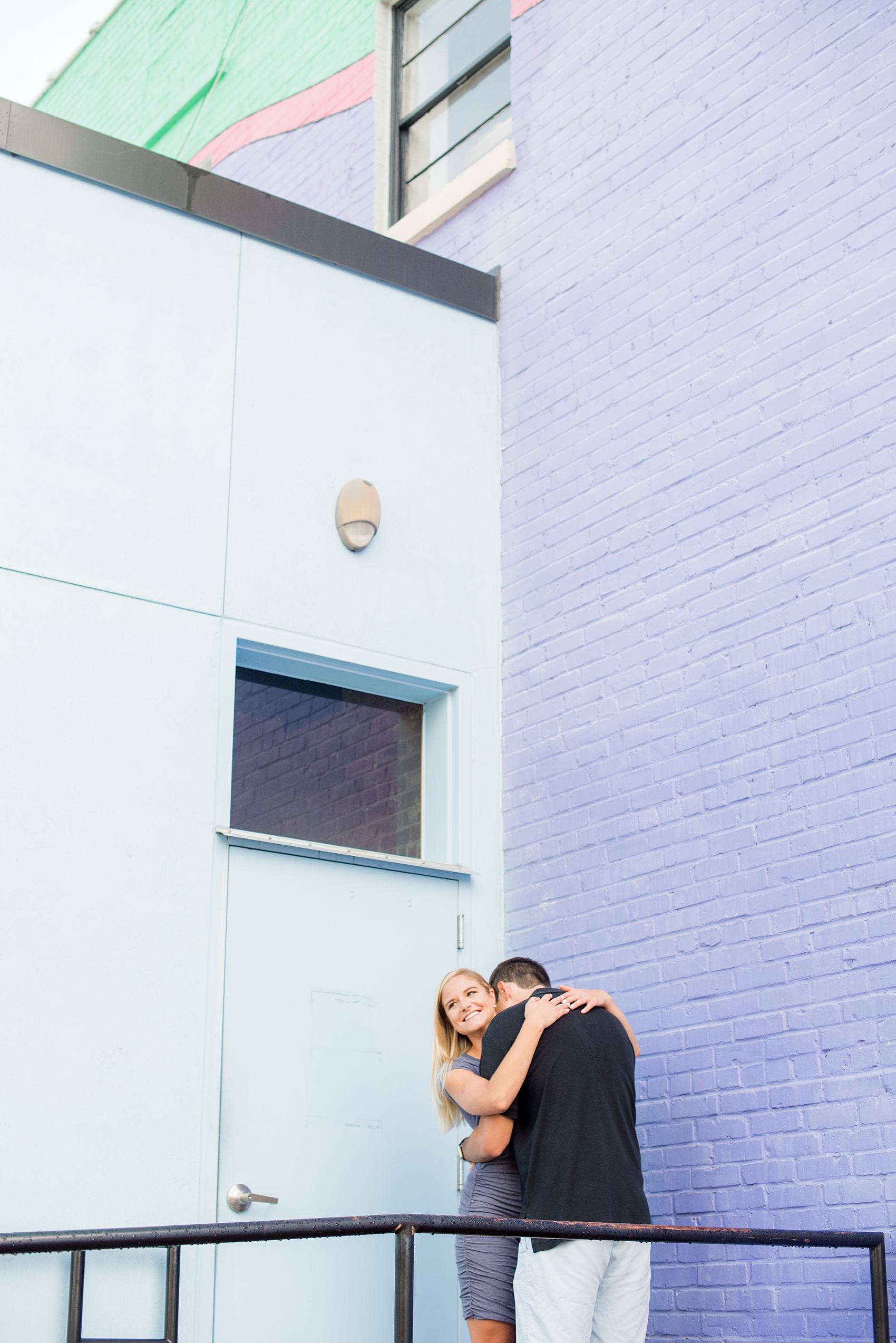 Mikkel Paige Photography pictures of a colorful engagement session in Chapel Hill North Carolina. The bride and groom hug in front of purple and light blue walls.