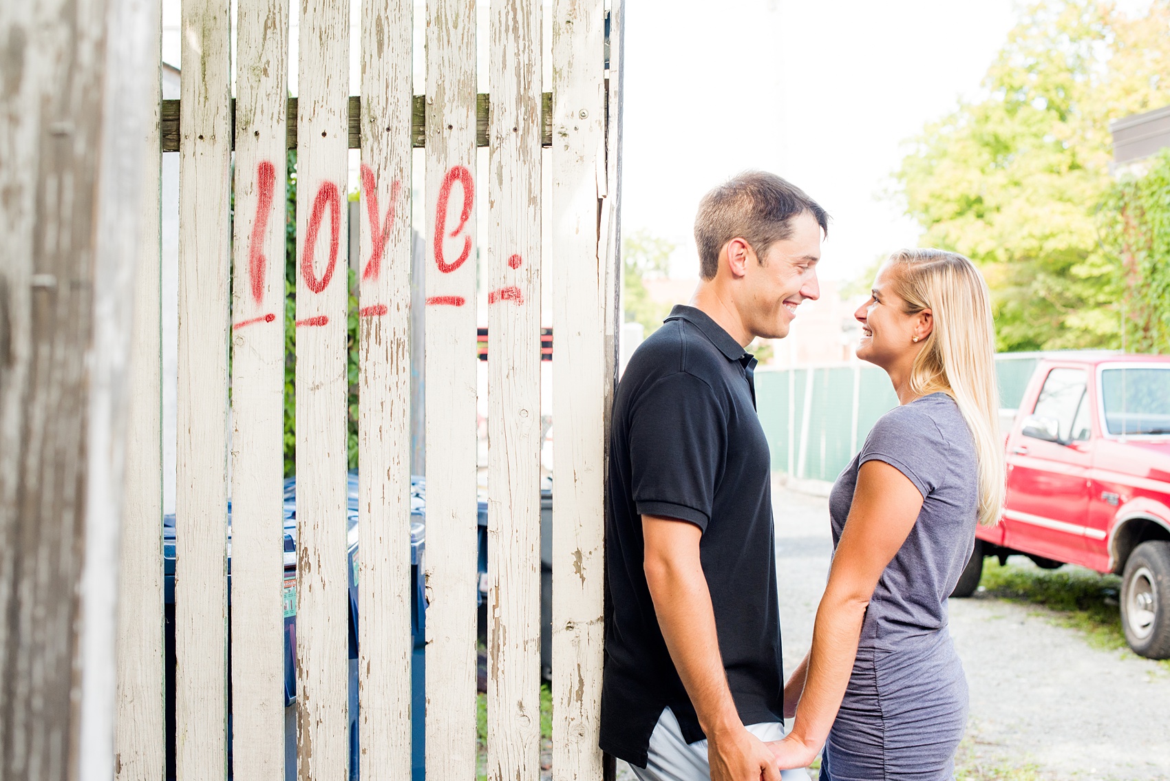 Mikkel Paige Photography pictures of a colorful engagement session in Chapel Hill North Carolina. The couple smiles next to LOVE graffiti. 