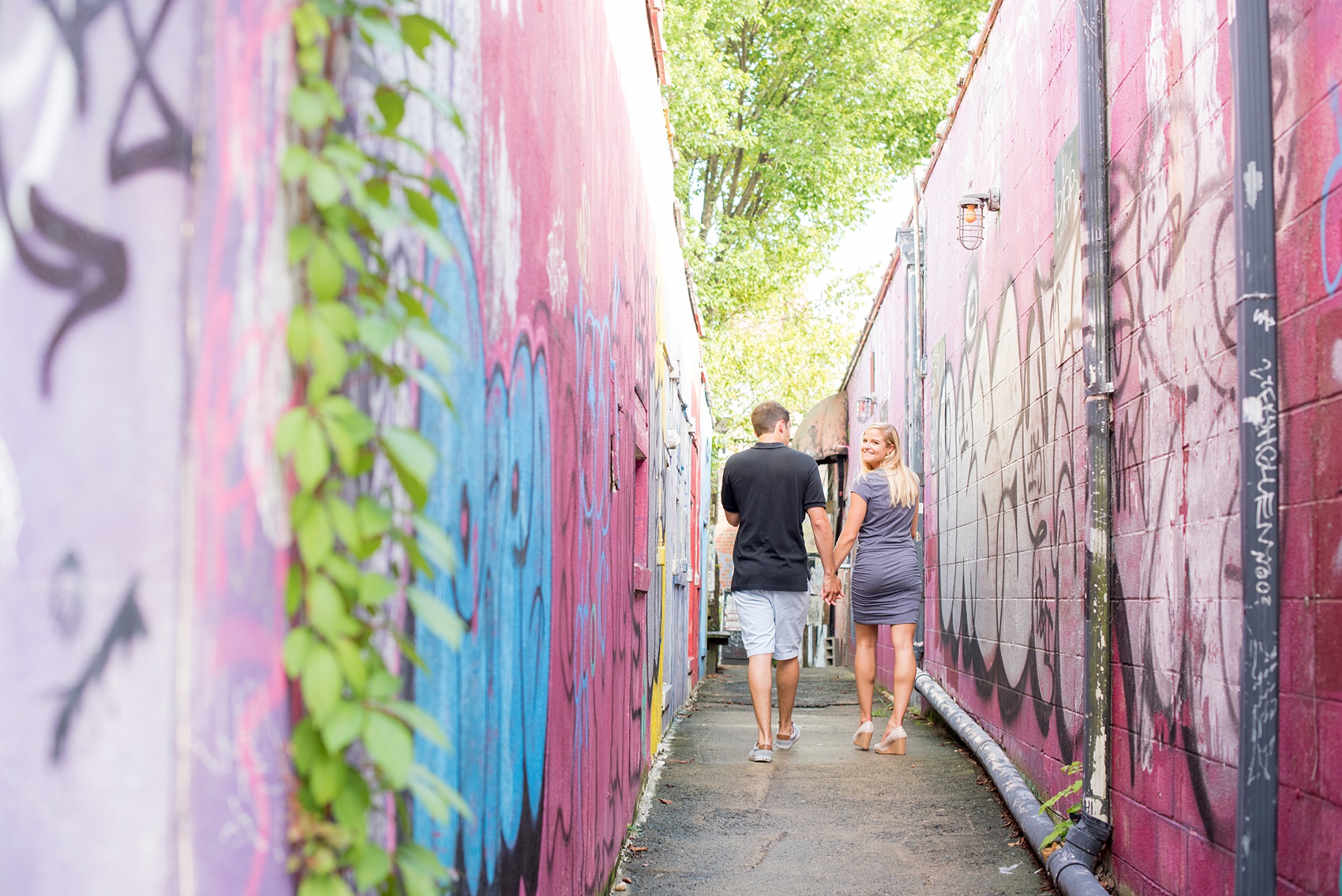 Mikkel Paige Photography pictures of a colorful engagement session in Chapel Hill North Carolina. The bride and groom walk through a vibrant graffiti walkway.