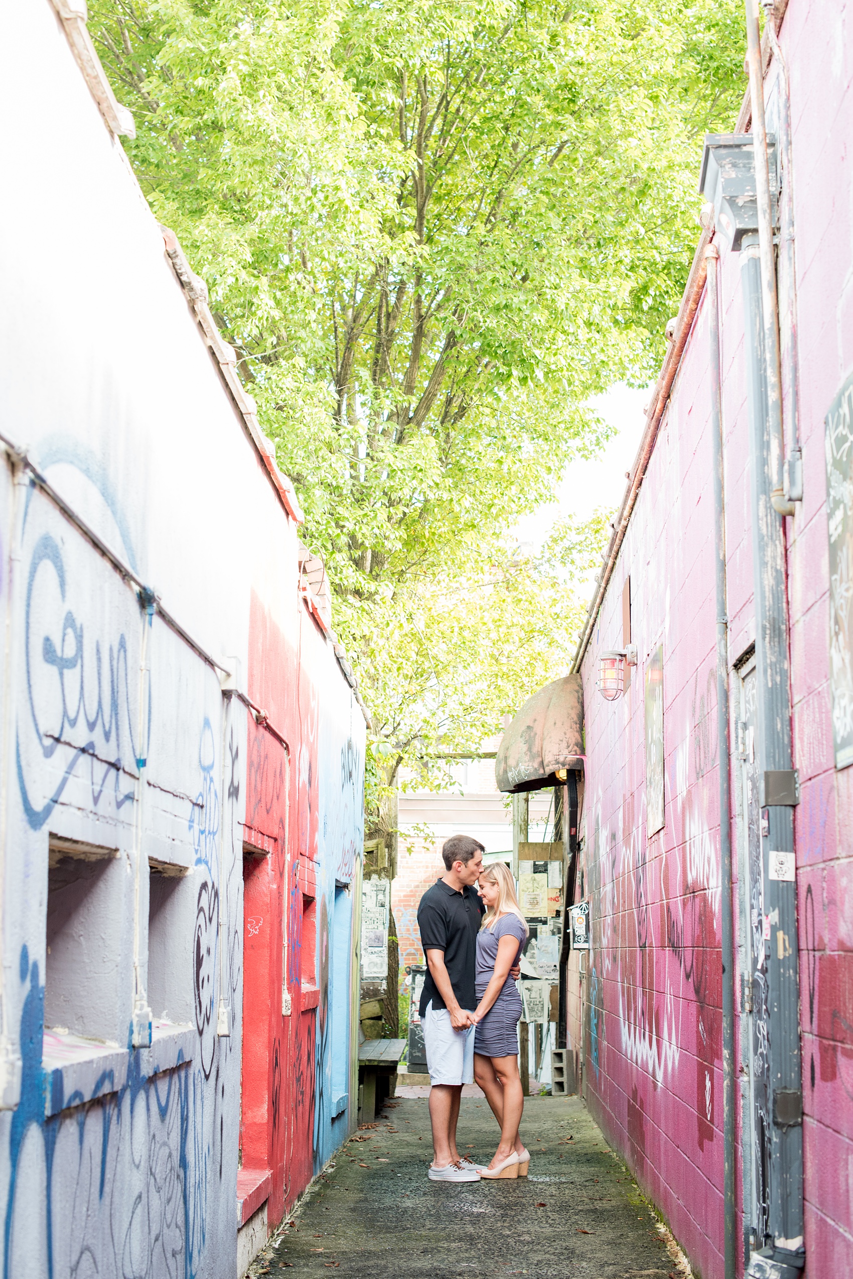 Mikkel Paige Photography pictures of a colorful engagement session in Chapel Hill North Carolina. The bride and groom walk through a vibrant graffiti tunnel.