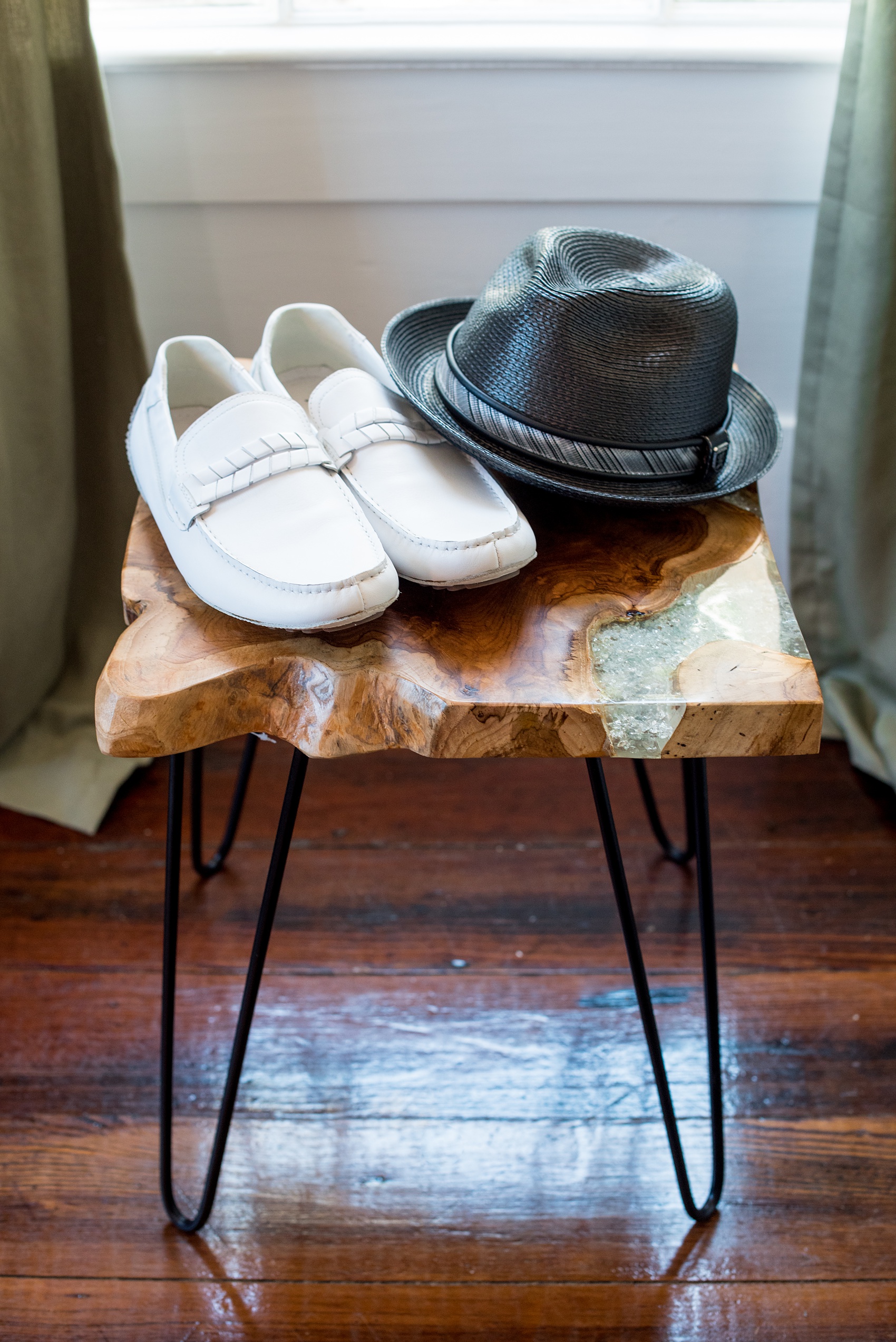 Mikkel Paige Photography pictures of a wedding at Leslie-Alford Mim's House in North Carolina for a Mad Dash Weddings event. Photo of the groom's white loafers and black fedora hat on a wood and gemstone side table.
