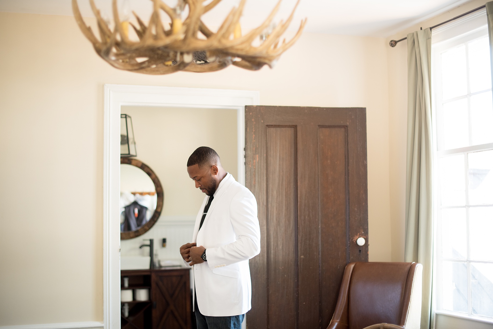 Mikkel Paige Photography pictures of a wedding at Leslie-Alford Mim's House in North Carolina for a Mad Dash Weddings event. Photo of the antler chandelier and getting ready in the groom's suite.