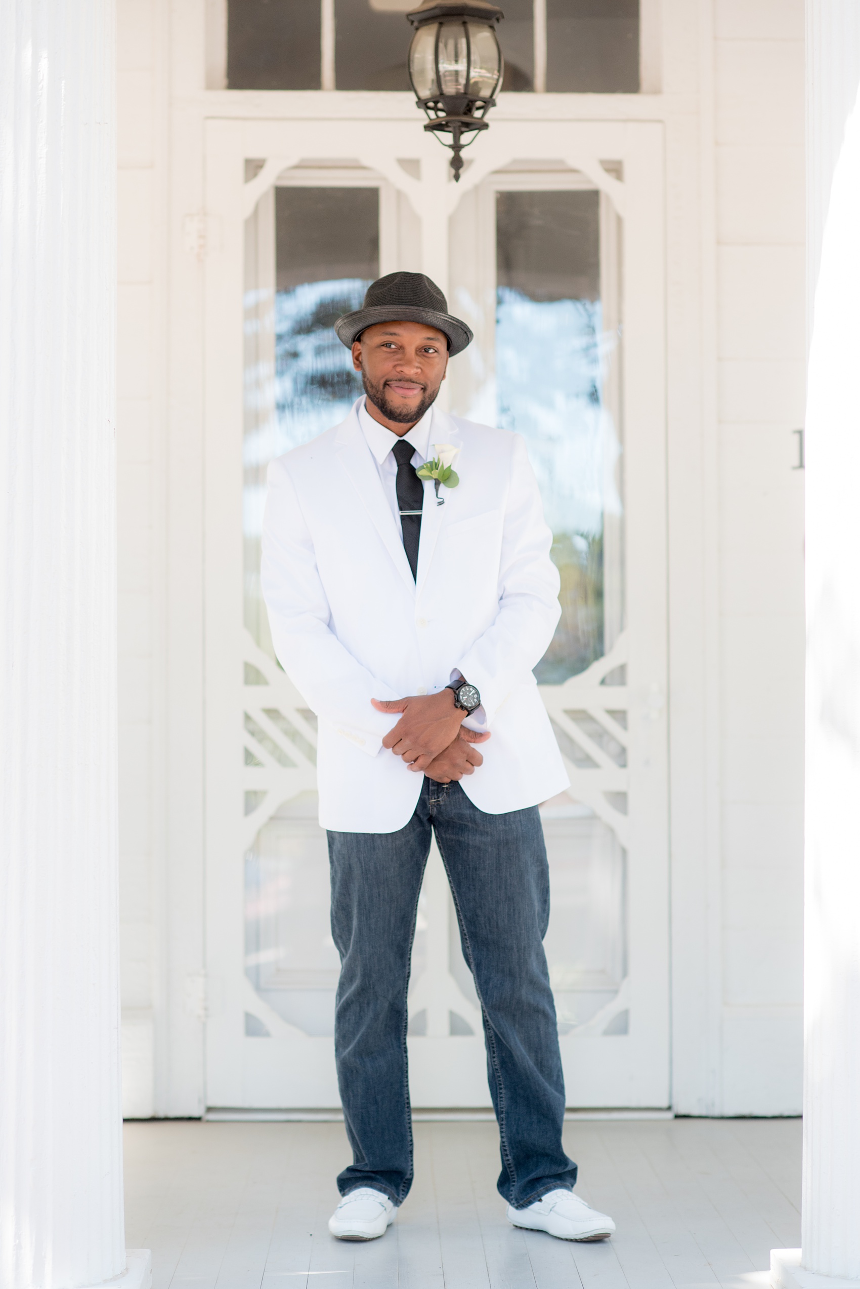 Mikkel Paige Photography pictures of a wedding at Leslie-Alford Mim's House in North Carolina for a Mad Dash Weddings event. Photo of the groom in a fedora, white coat and black tie, and casual dark jeans.