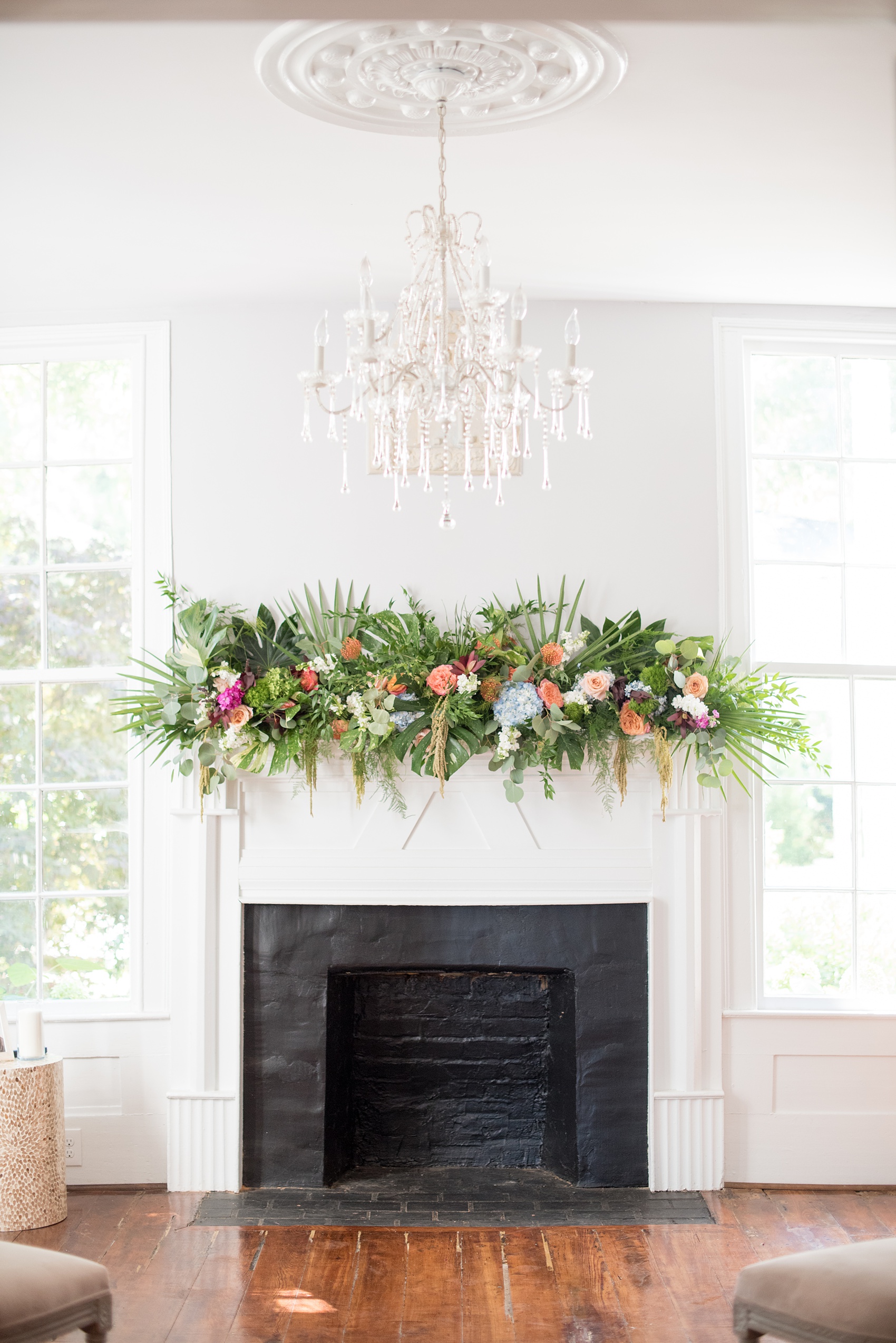 Mikkel Paige Photography pictures of a wedding at Leslie-Alford Mim's House in North Carolina for a Mad Dash Weddings event. Photo of the small elopement ceremony setup inside the historic home with a tropical floral arrangement above the fireplace.