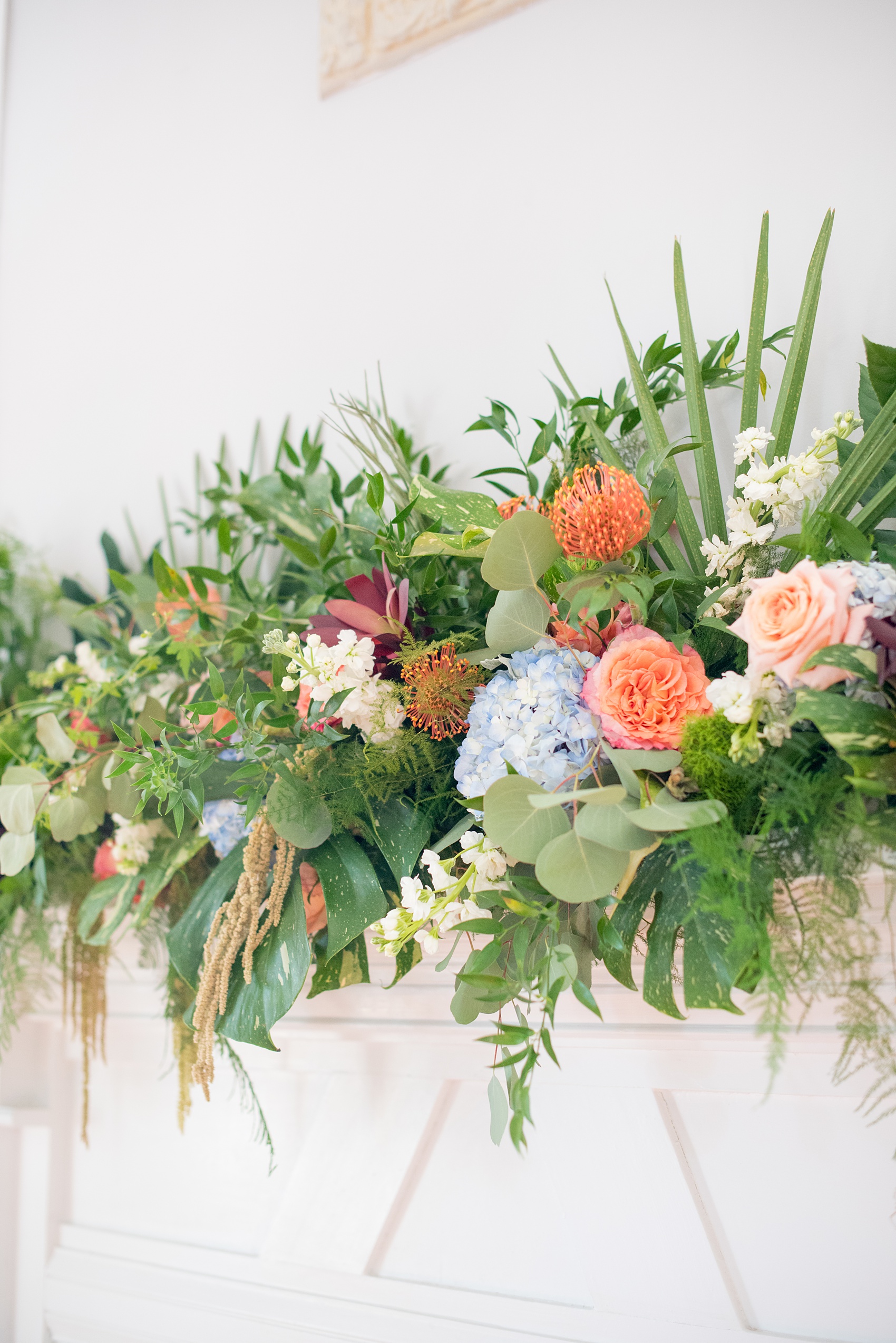 Mikkel Paige Photography pictures of a wedding at Leslie-Alford Mim's House in North Carolina for a Mad Dash Weddings event. Photo of tropical floral arrangement above the fireplace.