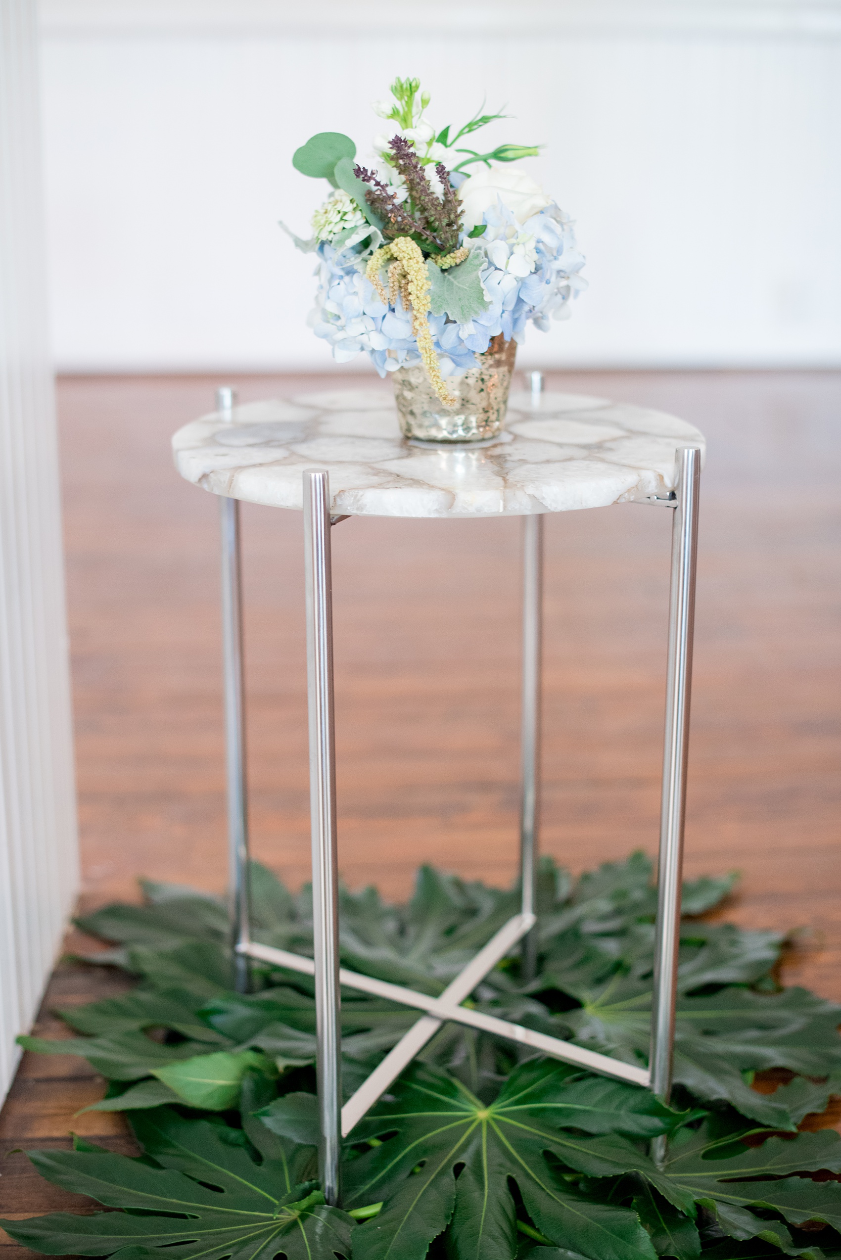 Mikkel Paige Photography pictures of a wedding at Leslie-Alford Mim's House in North Carolina for a Mad Dash Weddings event. Photo of decorative tropical leaves and marble table with floral arrangement.