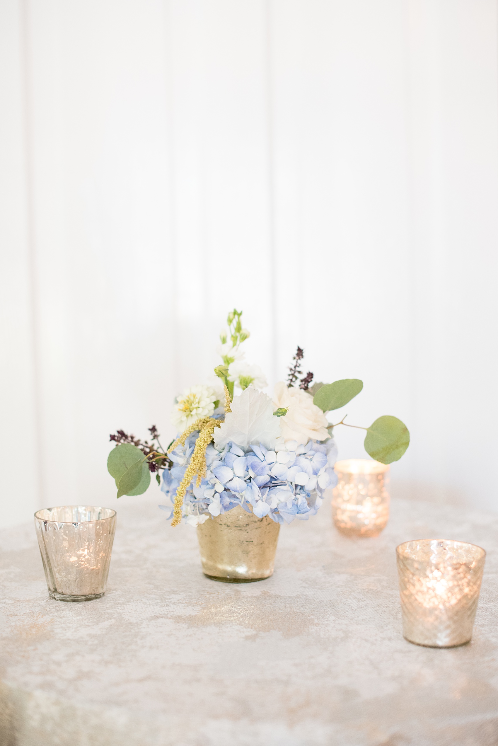 Mikkel Paige Photography pictures of a wedding at Leslie-Alford Mim's House in North Carolina for a Mad Dash Weddings event. Photo of the cocktail table setup with mercury glass votive candles and metallic linen.