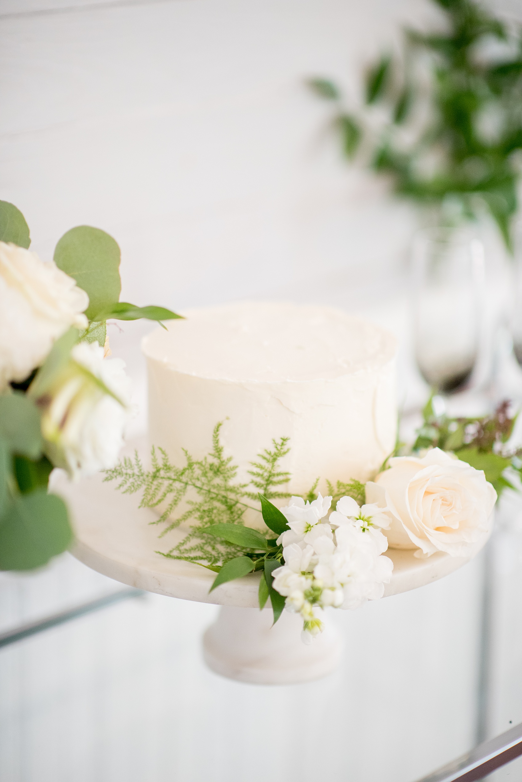 Mikkel Paige Photography pictures of a wedding at Leslie-Alford Mim's House in North Carolina for a Mad Dash Weddings event. Photo of the petite red-velvet, white frosted wedding cake adorned with flowers. 