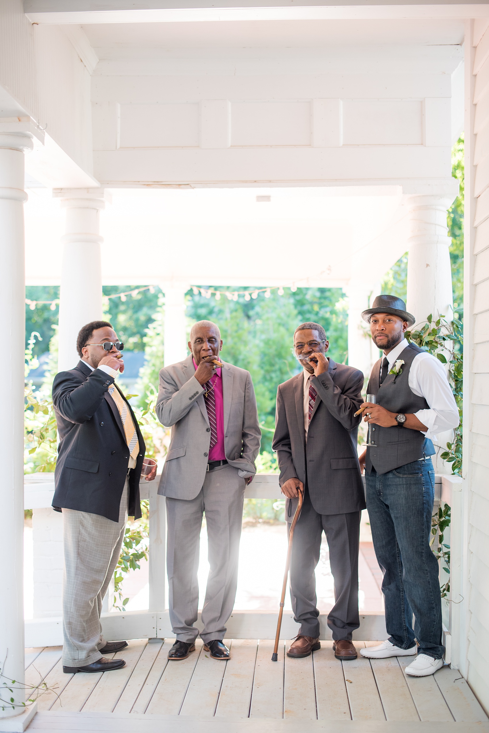 Mikkel Paige Photography pictures of a wedding at Leslie-Alford Mim's House in North Carolina for a Mad Dash Weddings event. Photo of the groom and men smoking cigars on the venue porch.