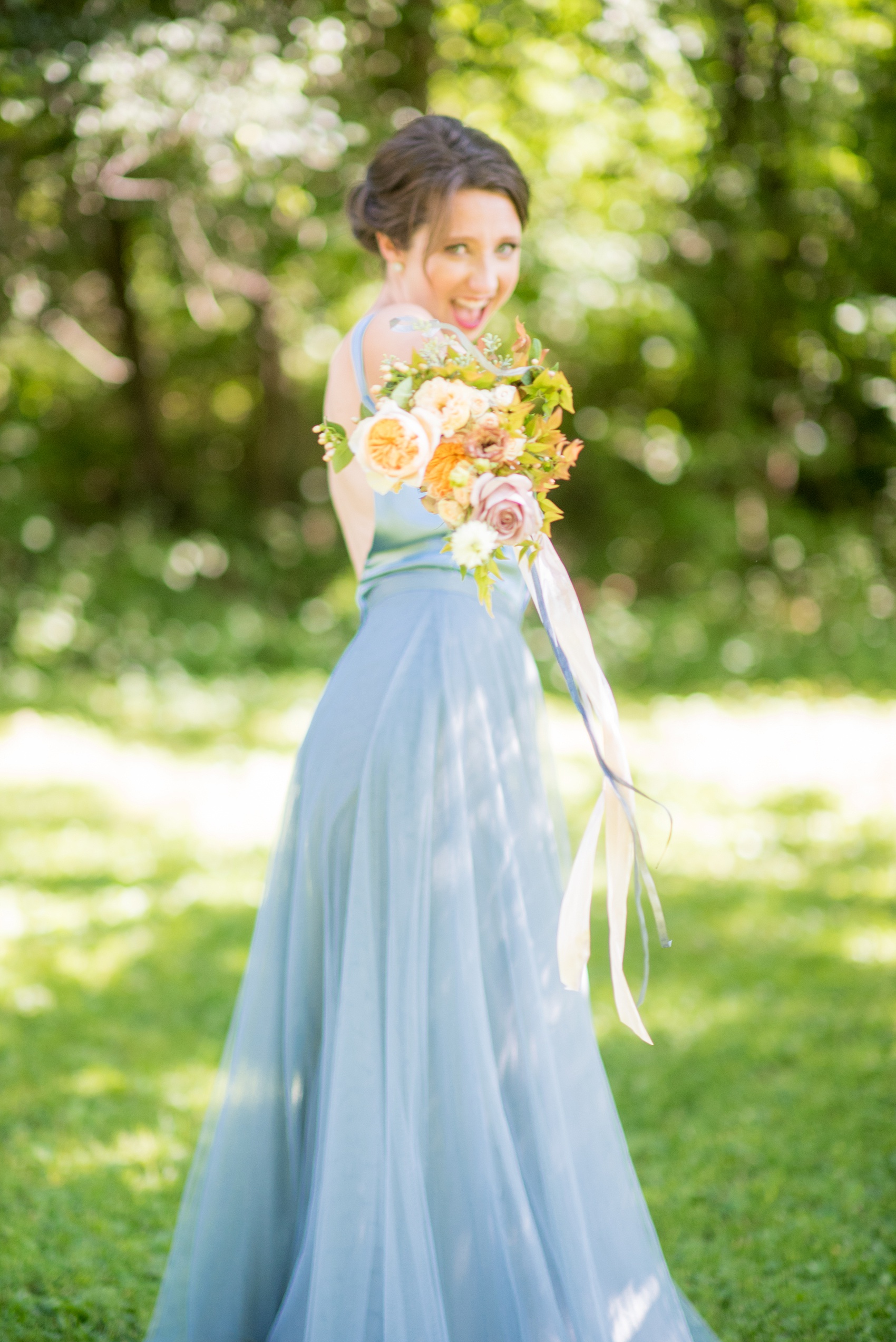 Mikkel Paige Photography photos from a Southwood Estate Wedding in Germantown, New York in the Hudson Valley. Playful picture of a bridesmaid in a cornflower blue gown and top and her colorful bouquet.