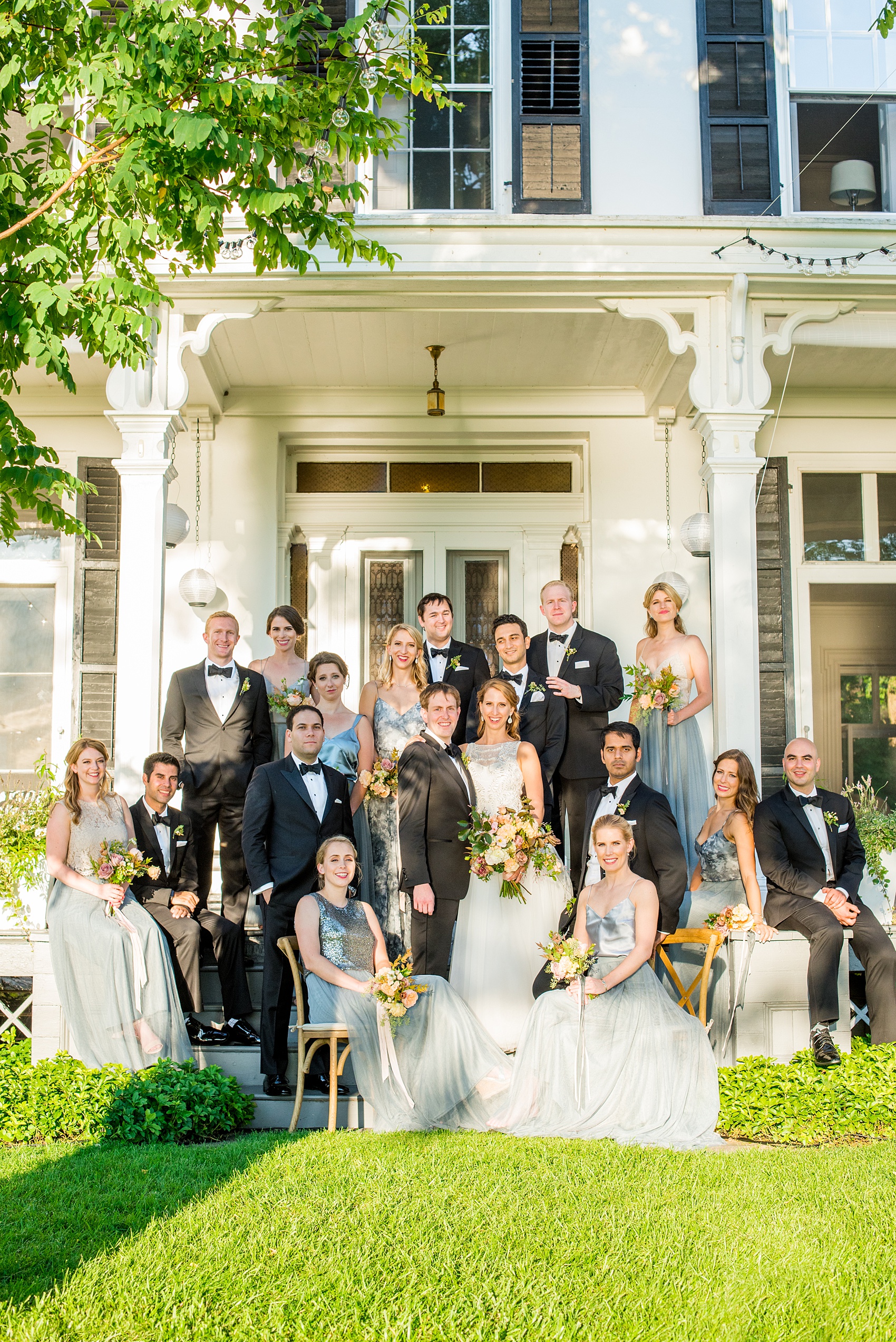 Mikkel Paige Photography photos from a Southwood Estate Wedding in Germantown, New York in the Hudson Valley. Picture of the bride and her bridal party in cornflower blue skirts with mismatched tops and the groomsmen in classic black tuxedos and bow ties on the front porch of the historic home.