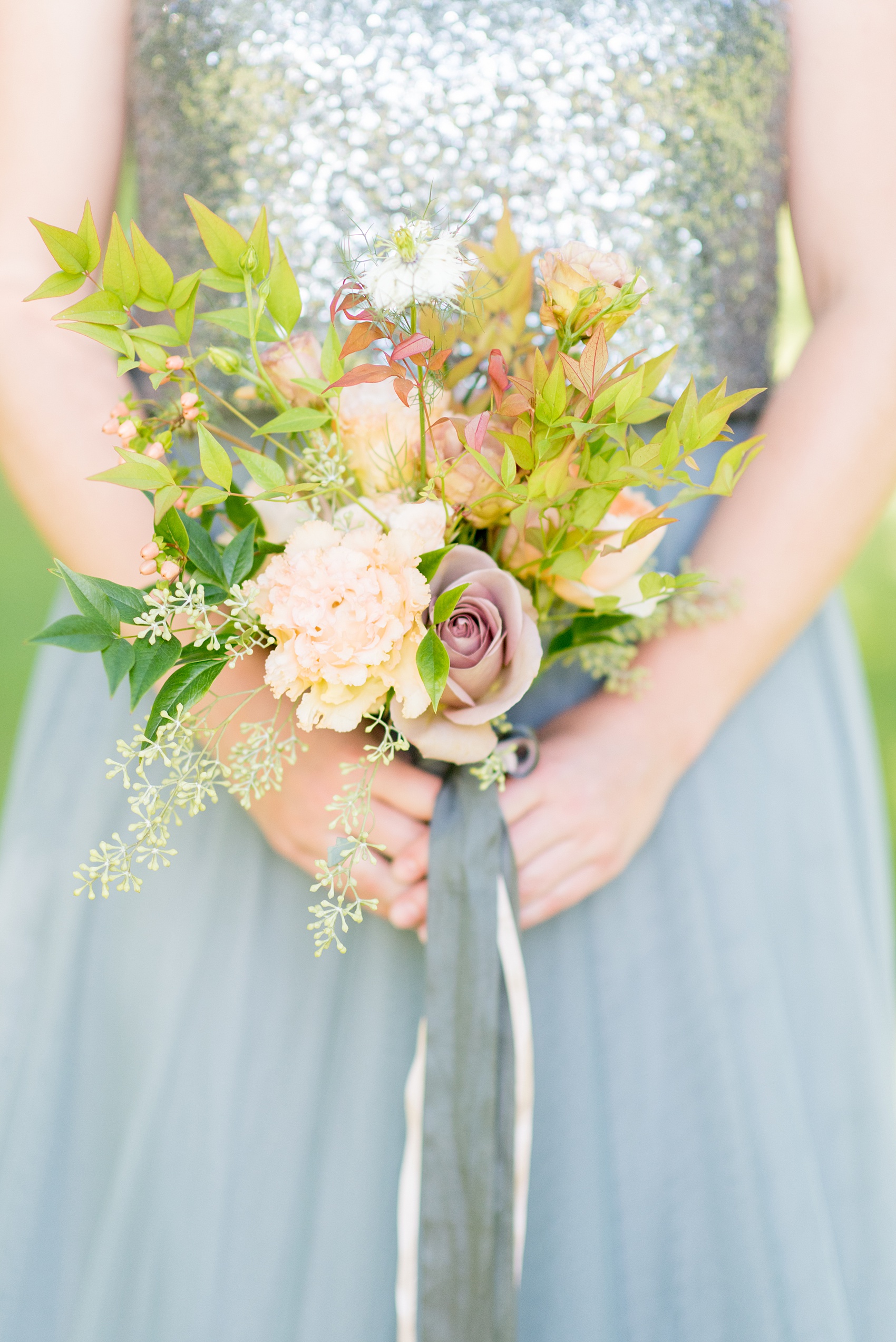 Mikkel Paige Photography photos from a Southwood Estate Wedding in Germantown, New York in the Hudson Valley. Picture of a bridesmaid in a cornflower blue gown and sequin top and her colorful bouquet tied with long silk ribbons.