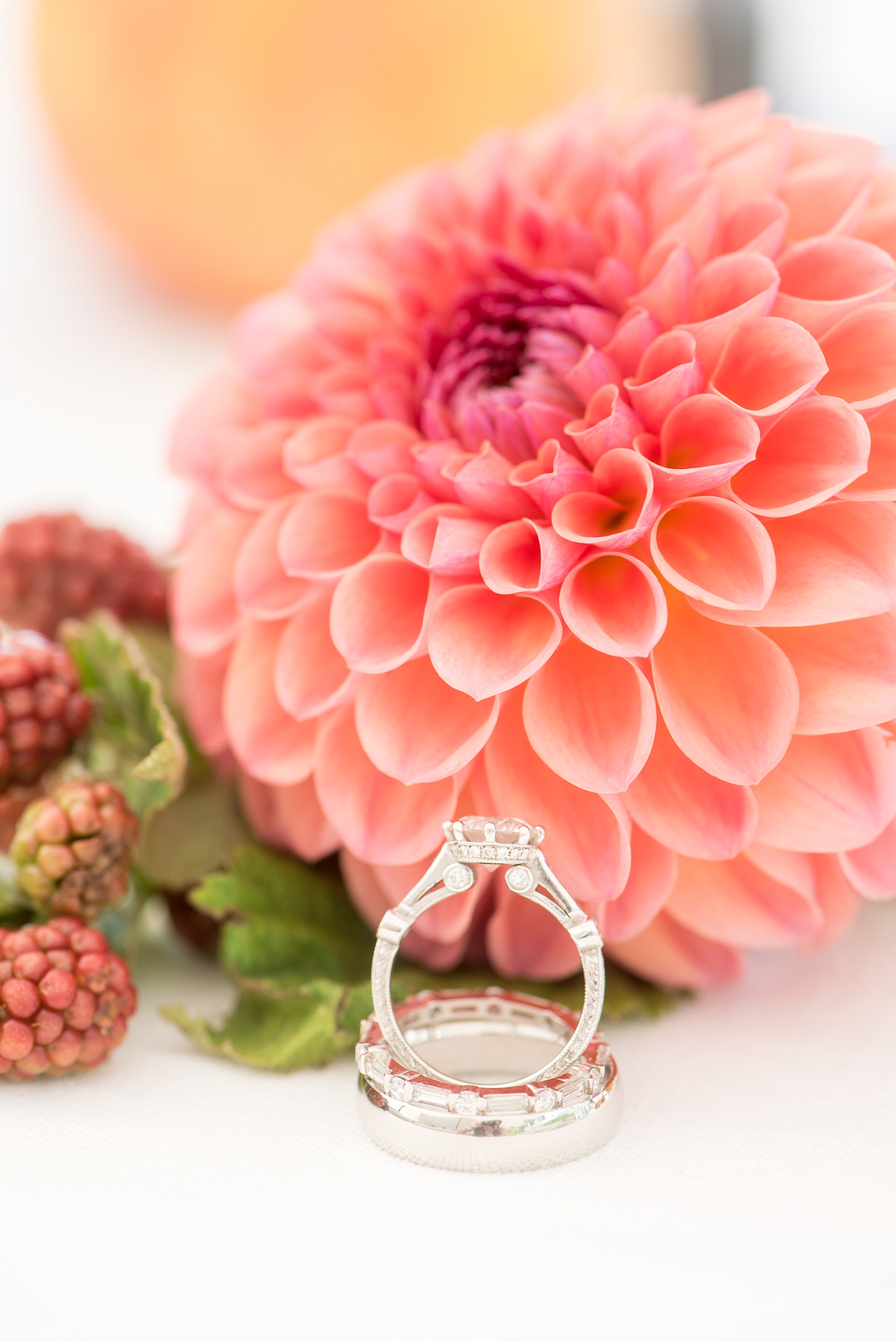 Mikkel Paige Photography photos from a wedding at Southwood Estate in Germantown, New York. Detail picture of the bride's engagement ring detail and wedding bands with a peach dahlia flower.