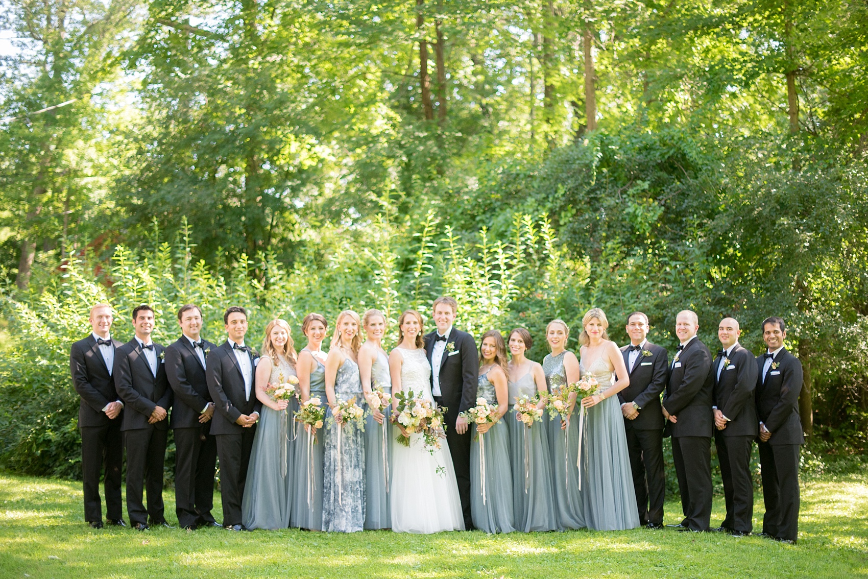 Mikkel Paige Photography photos from a wedding at Southwood Estate in Germantown, New York. Picture of the bride and groom with their wedding party. The bridal party wore mismatched blue gowns.