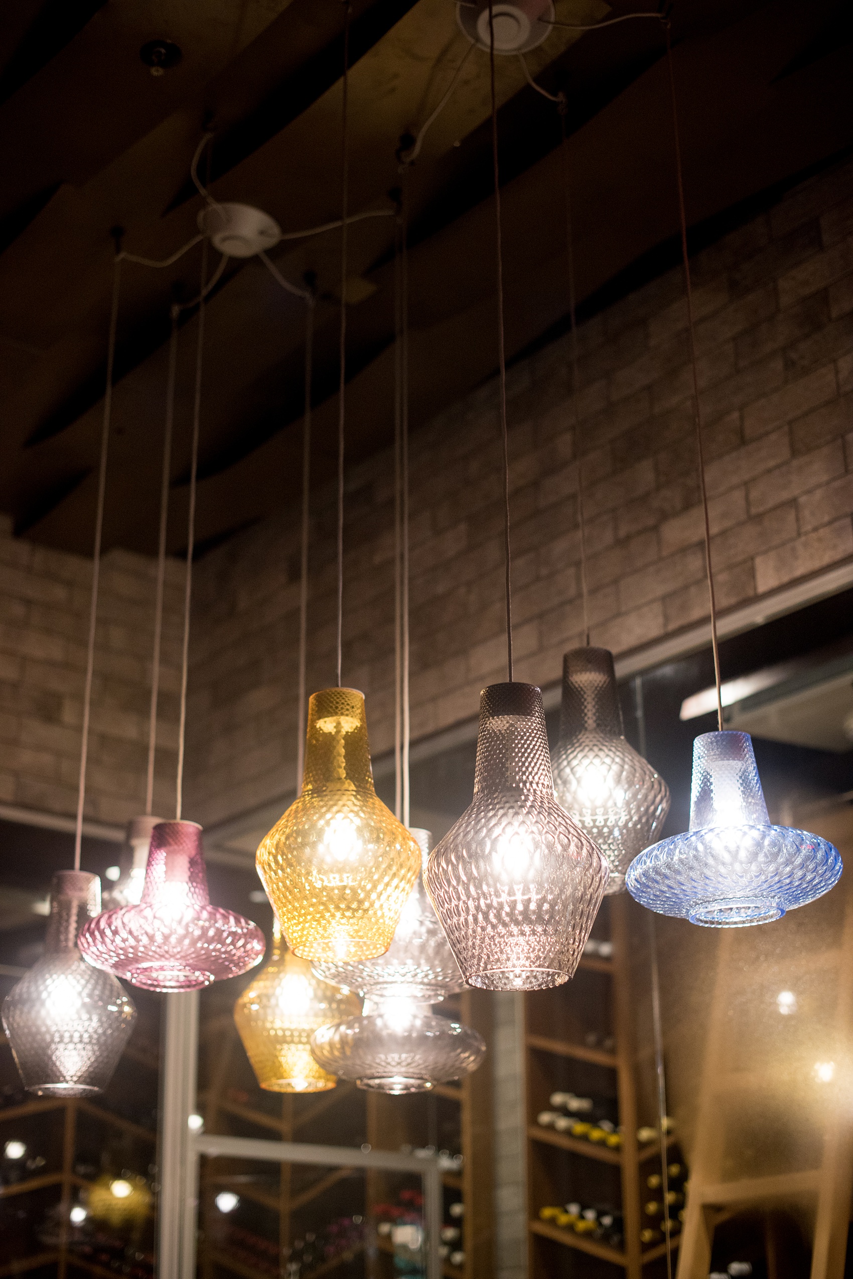 Photos of Vidrio restaurant in Raleigh, NC by Mikkel Paige Photography. Wedding venue in North Carolina with mediterranean and Spanish inspired art and interior design. Picture of different colored glass lamp hangings.