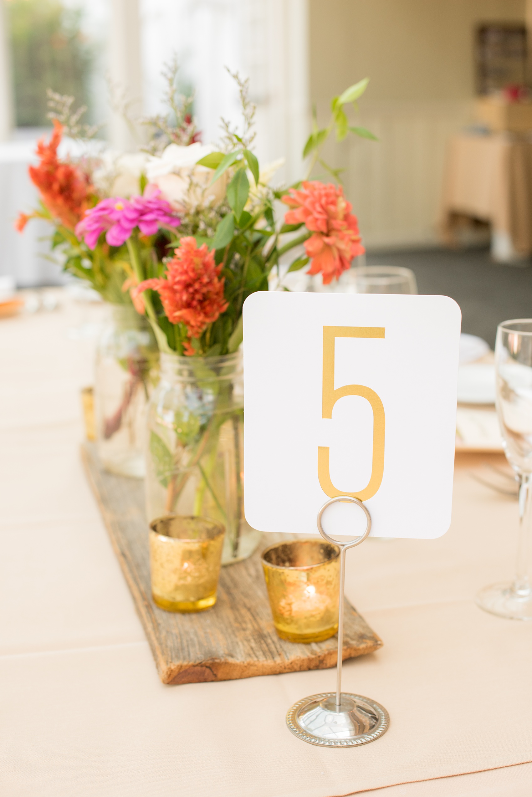 Mikkel Paige Photography photos of a wedding at Crabtree Kittle's House. Picture of the table centerpieces with gold numbers, wildflowers and mercury glass votive candleholders. 