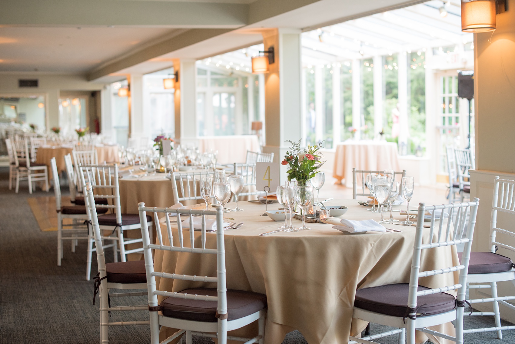 Mikkel Paige Photography photos of a wedding at Crabtree Kittle's House. Picture of the tables and centerpieces with gold numbers, wildflowers and mercury glass votive candleholders. 