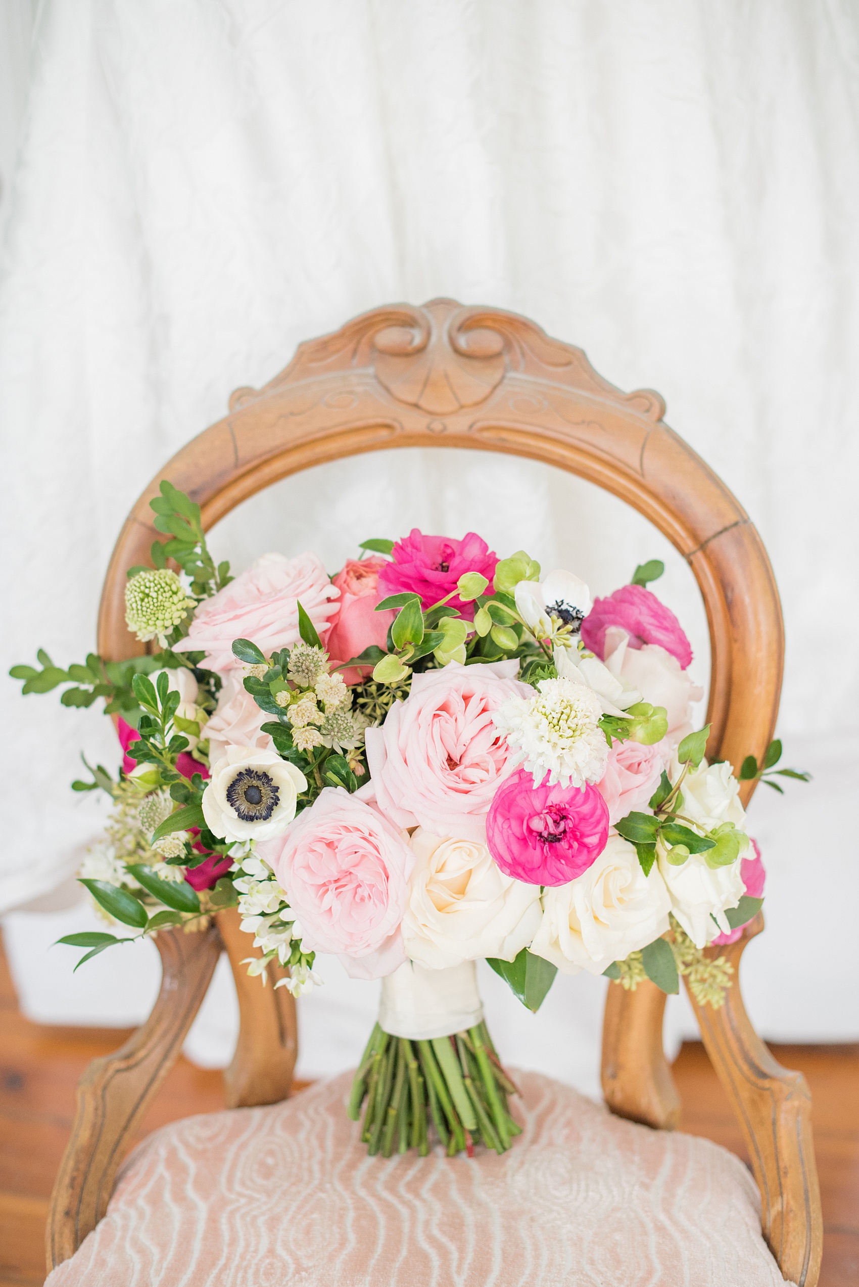 Mikkel Paige Photography pictures from a wedding at Merrimon-Wynne House in Raleigh, NC. Photo of the bride's bouquet by Eclectic Sage. It includes white anemones, light pink roses, hot pink ranunculus, and scabiosa.