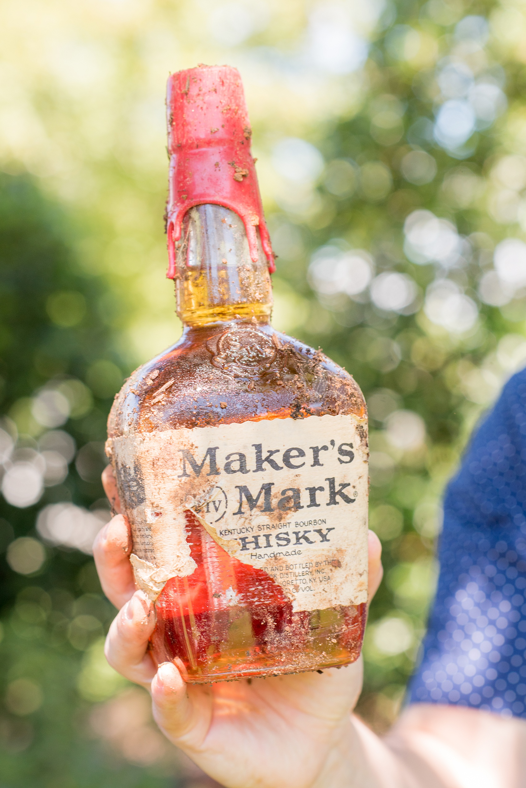 Mikkel Paige Photography pictures from a wedding at Merrimon-Wynne House in Raleigh, NC. Photo of the southern tradition of burying the bourbon dig up with the groom!