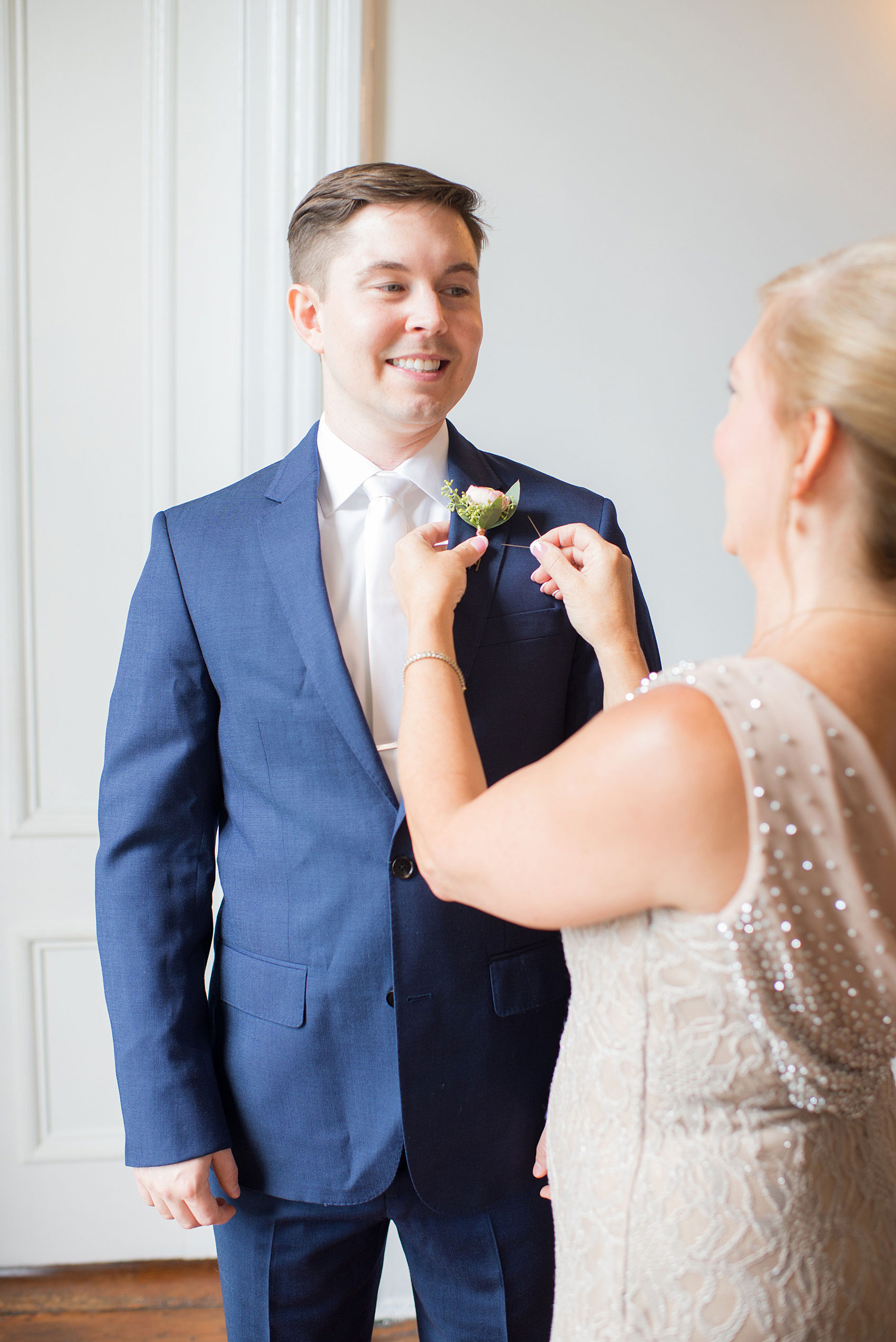 Mikkel Paige Photography pictures from a wedding at Merrimon-Wynne House in Raleigh, NC. Photo of the groom's mother pinning on his boutonniere.