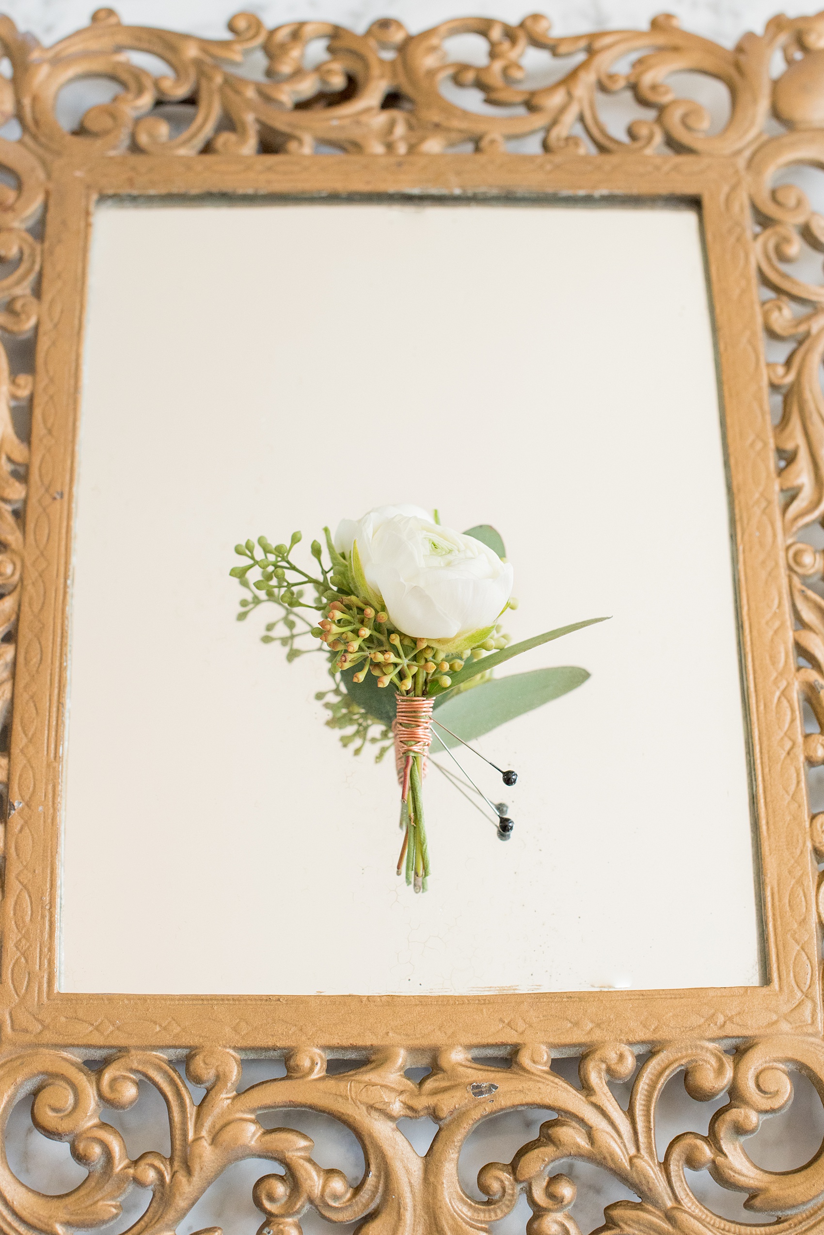 Mikkel Paige Photography pictures from a wedding at Merrimon-Wynne House in Raleigh, NC. Photo of white ranunculus boutonniere with eucalyptus, tied with copper wire.