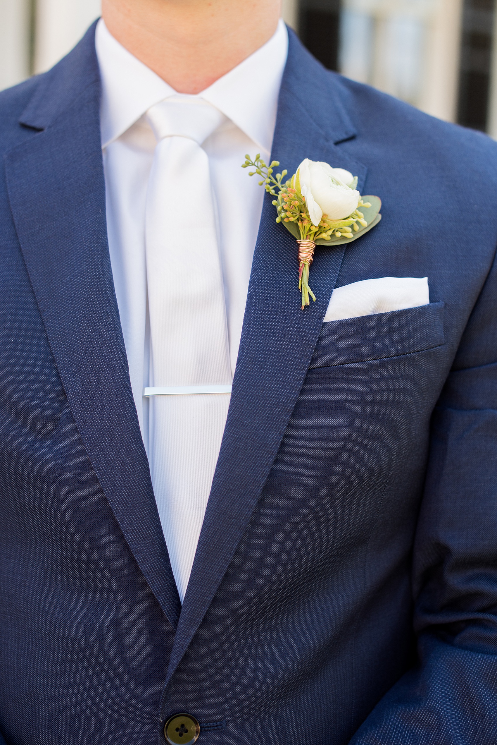 Mikkel Paige Photography pictures from a wedding at Merrimon-Wynne House in Raleigh, NC. Detail photo of the grooms's blue linen suit, white boutonniere tied with copper wire and skinny tie.