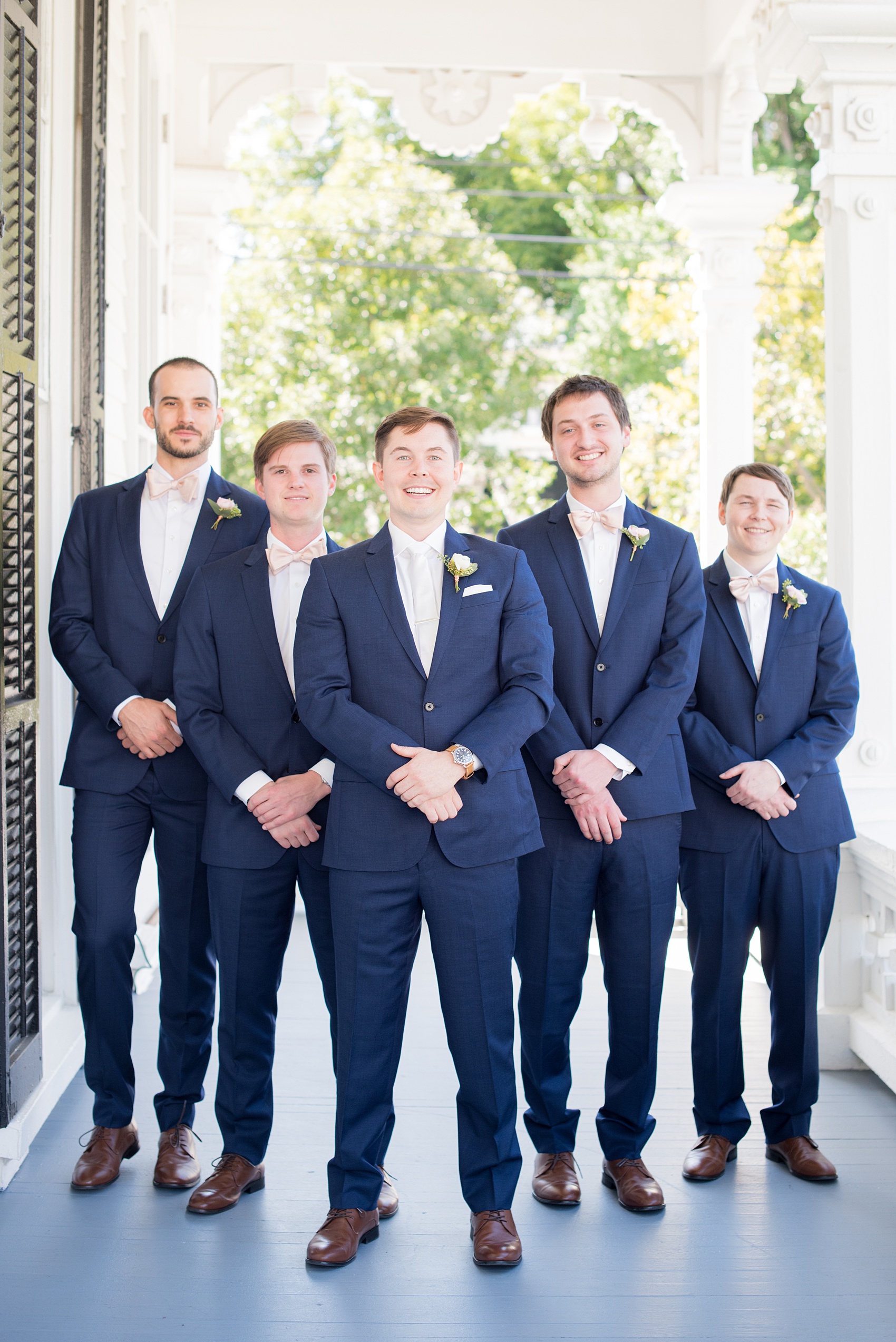 Mikkel Paige Photography pictures from a wedding at Merrimon-Wynne House in Raleigh, NC. Photo of the groomsmen in blue linen suits, pink boutonnieres tied with copper wire and pink bow ties.