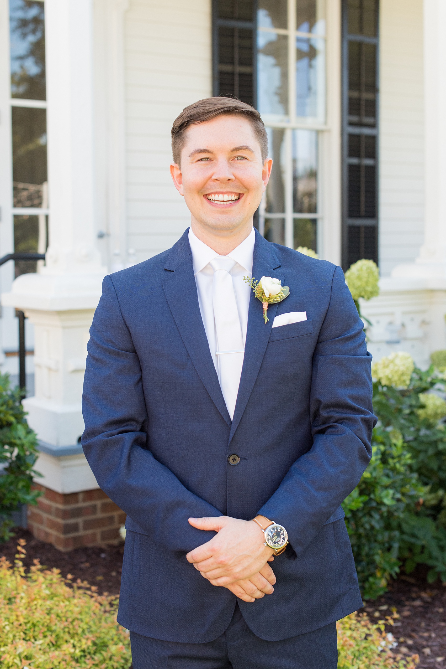 Mikkel Paige Photography pictures from a wedding at Merrimon-Wynne House in Raleigh, NC. Photo of the groom in a blue linen suit, white tie and boutonniere tied with copper wire.