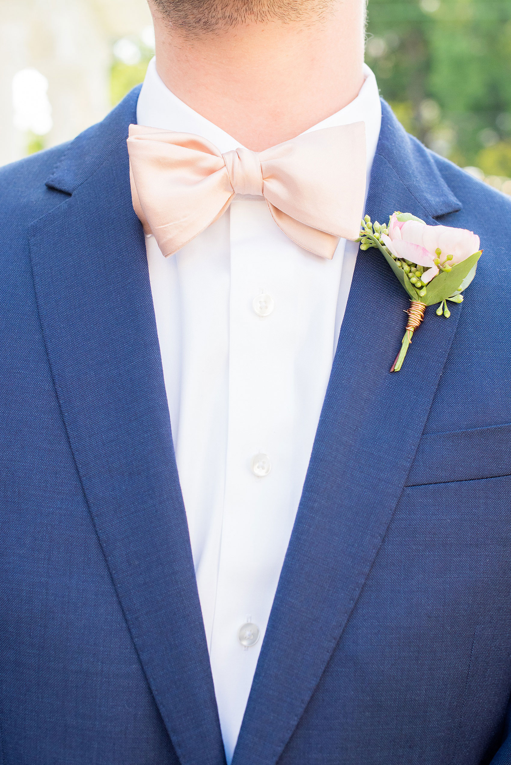 Mikkel Paige Photography pictures from a wedding at Merrimon-Wynne House in Raleigh, NC. Detail photo of the groomsman's blue linen suit, pink boutonniere tied with copper wire and pink bow tie.