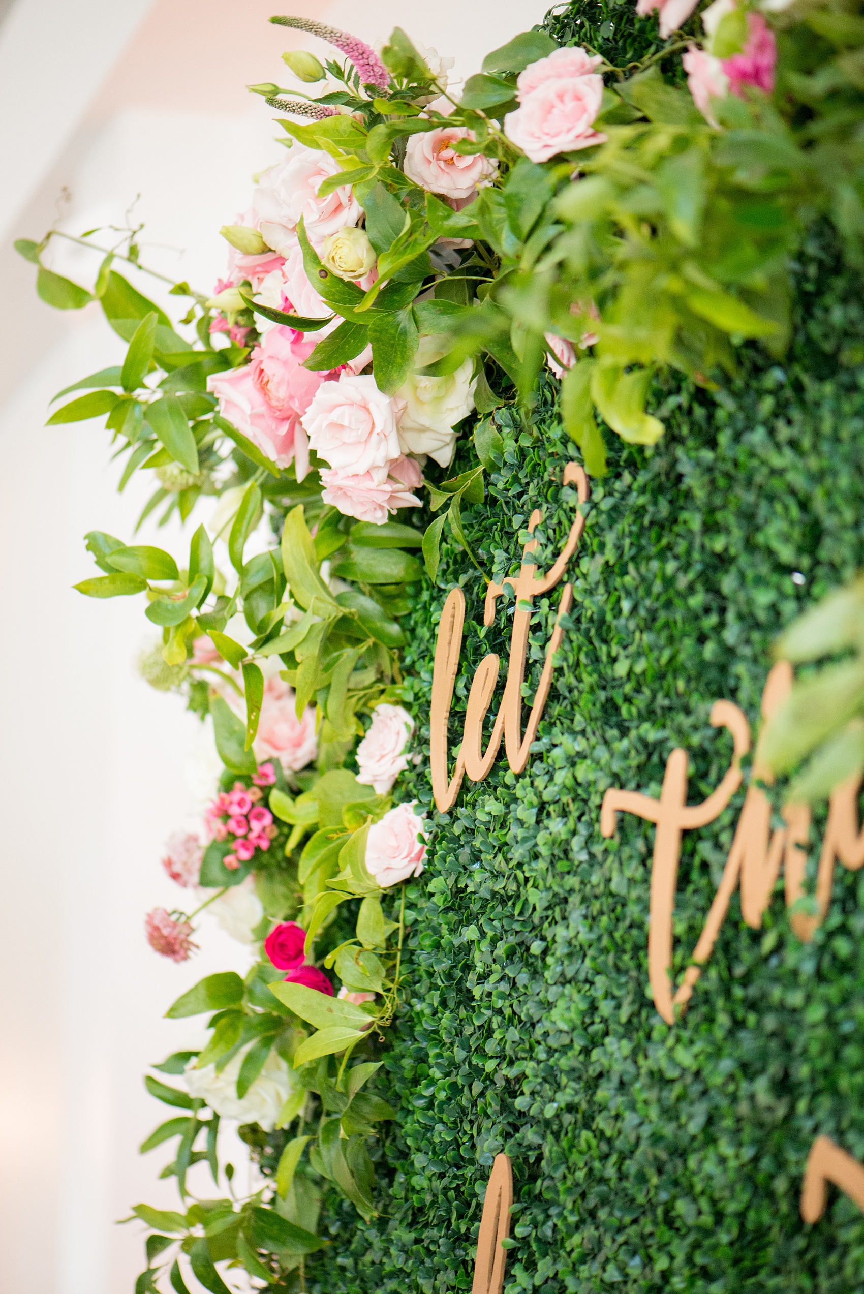 Mikkel Paige Photography pictures from a wedding at Merrimon-Wynne House in Raleigh, NC. Photo of the boxwood greenery backdrop with pink roses and script wood gold letters at the ceremony.