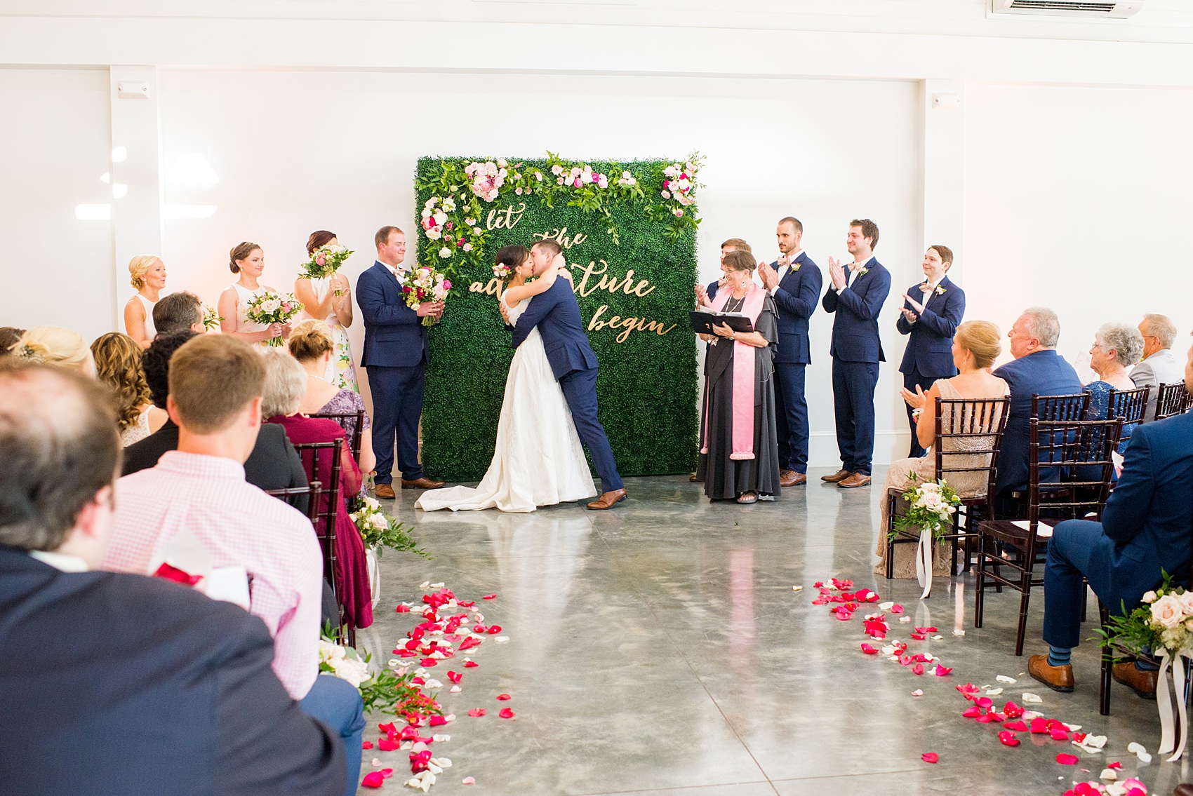 Mikkel Paige Photography pictures from a wedding at Merrimon-Wynne House in Raleigh, NC. Photo of the bride and groom's first kiss after their ceremony with a greenery backdrop.